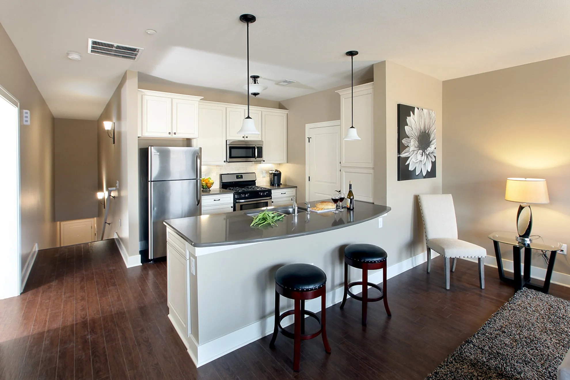 Modern kitchen with sleek countertops, stainless steel appliances, and stylish bar seating adjacent to a cozy living area.