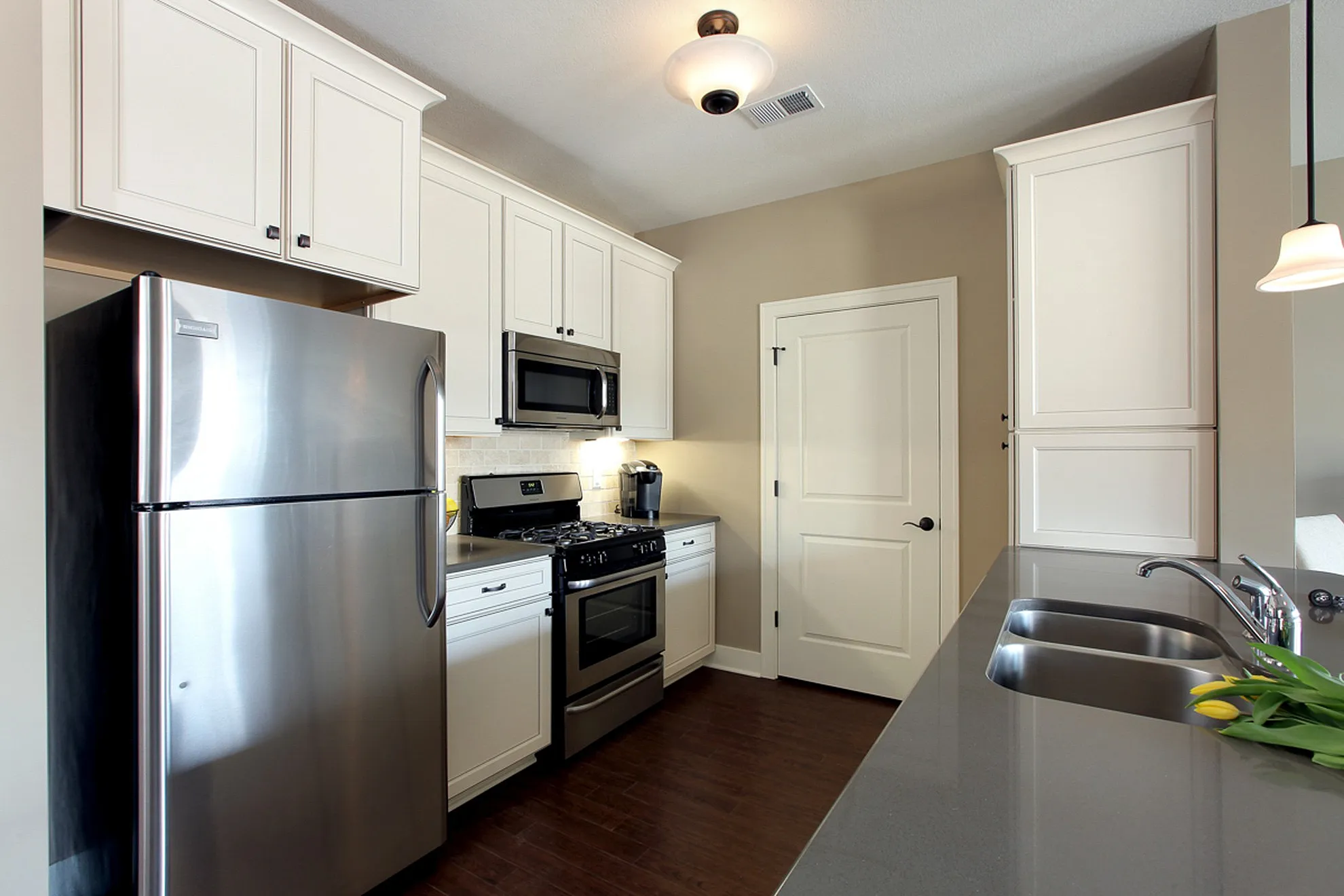 Modern kitchen showcasing sleek stainless steel appliances, pristine white cabinetry, and a stylish gray countertop with a double sink.