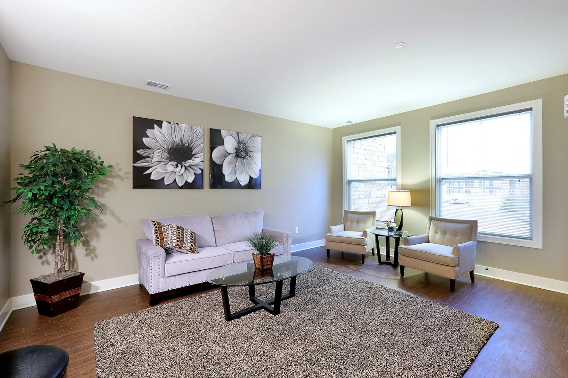 Bright and inviting living room with modern decor, a comfortable sofa, stylish chairs, and large windows providing ample natural light.