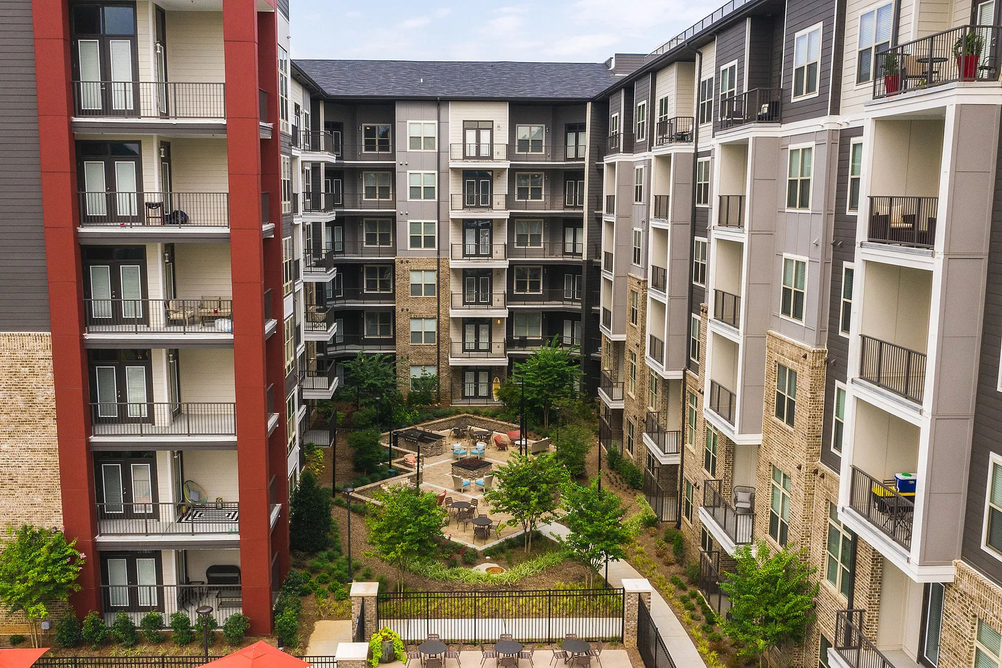 Modern apartment complex with multi-story buildings featuring elegant balconies and a lush central courtyard for relaxation and socializing.