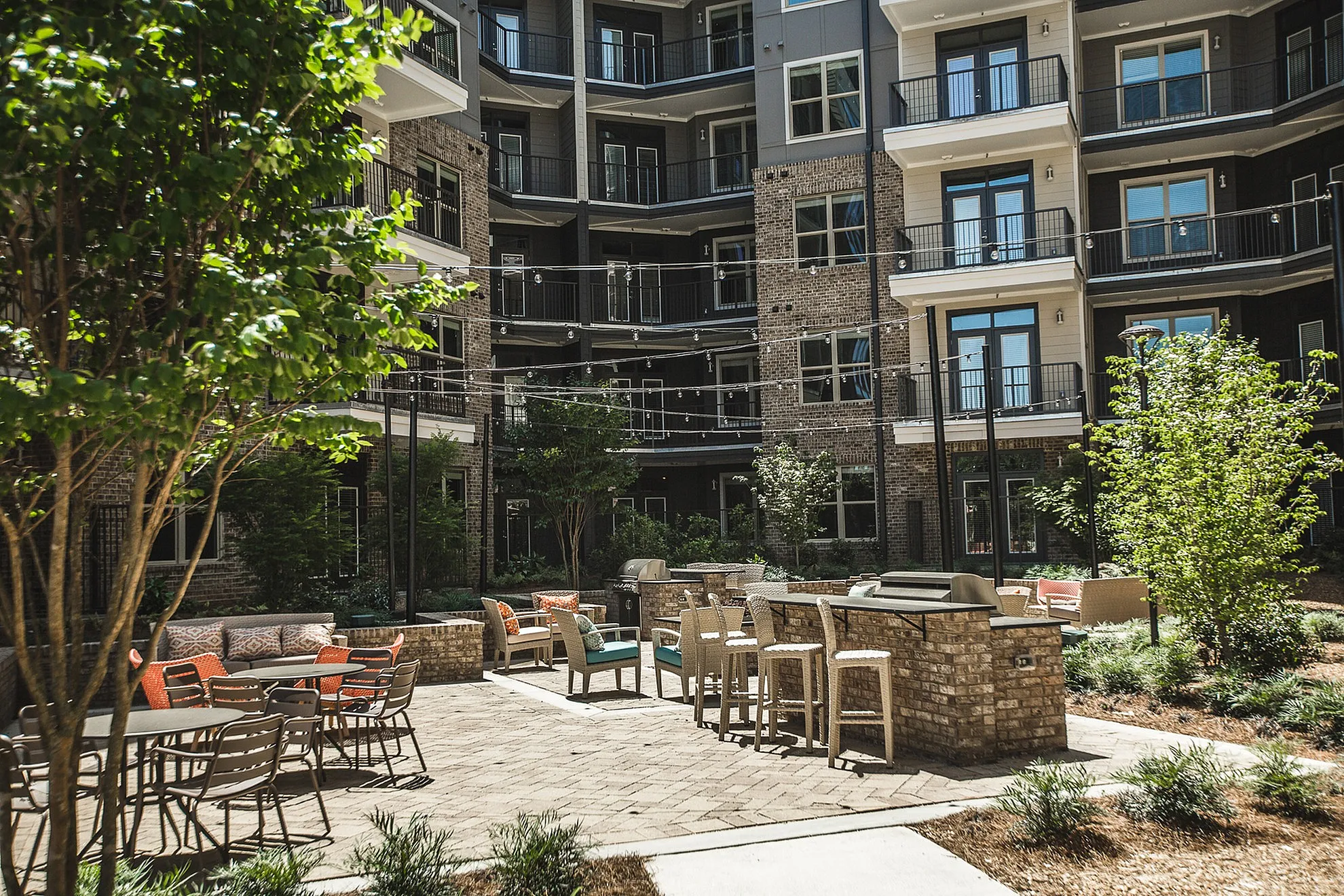 Charming apartment courtyard with stylish seating, lush greenery, and ambient string lights perfect for relaxation and entertainment.