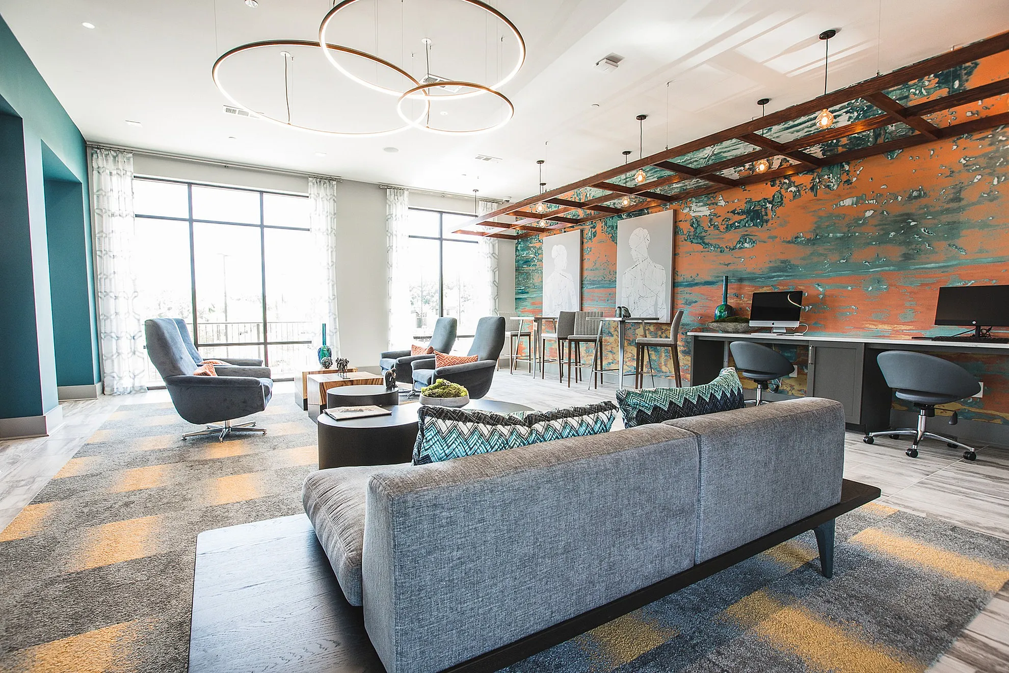 Modern lounge area with stylish geometric decor, cozy seating, bold artwork, and natural light from large windows.