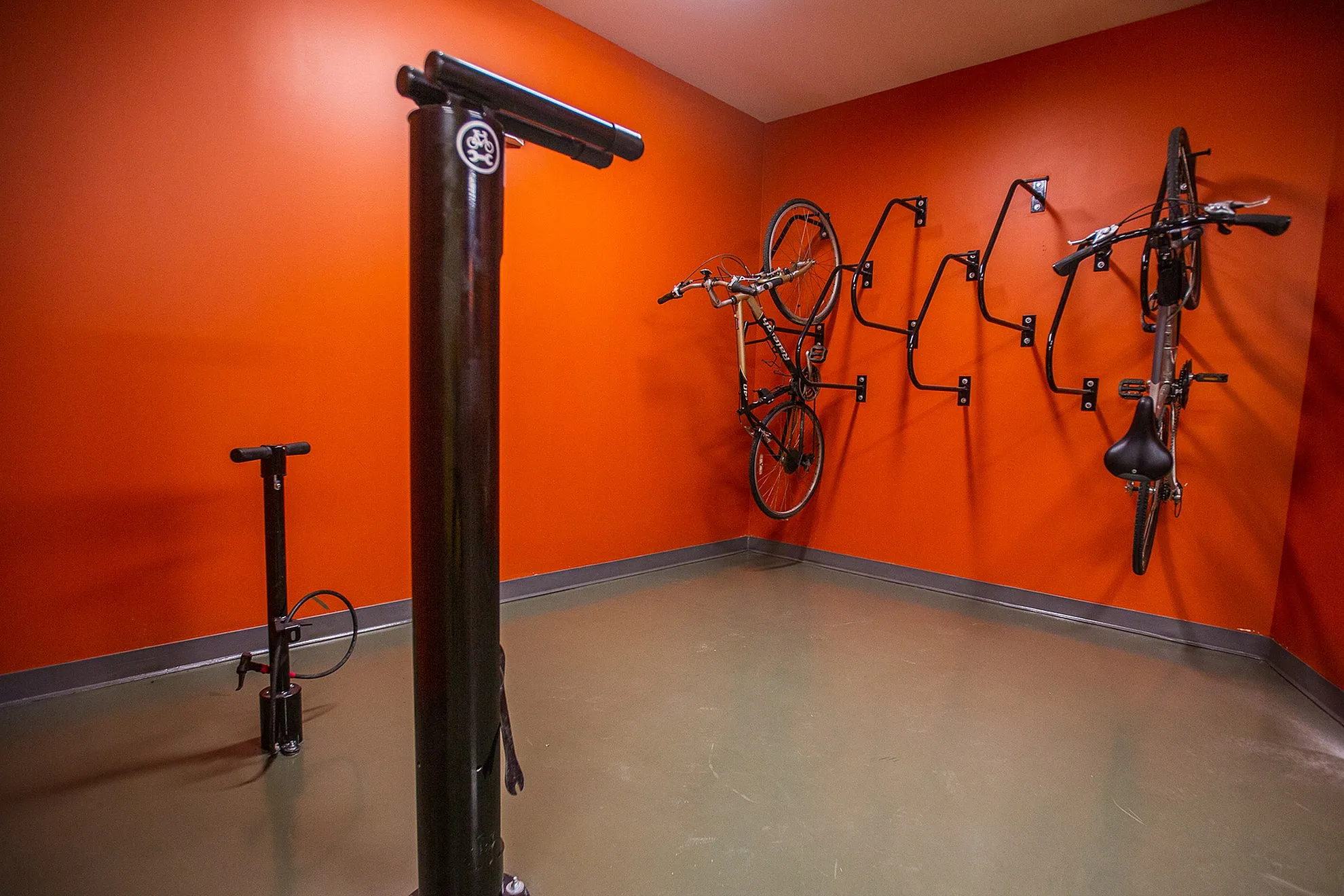 Vibrant orange bike storage room featuring secure wall-mounted racks and convenient pump station.