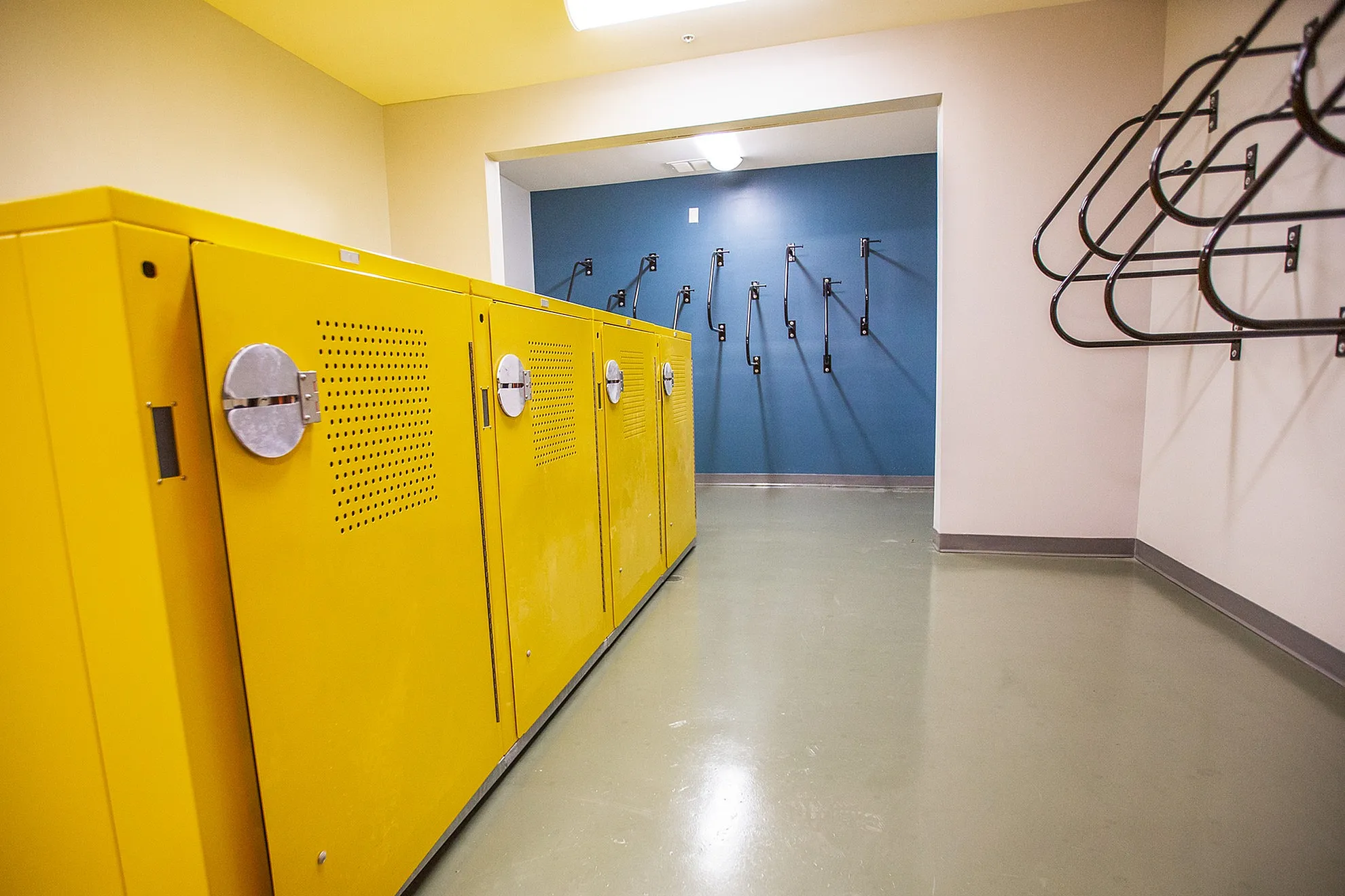 Modern apartment amenities featuring bright yellow bike storage lockers and secure wall-mounted racks, offering convenience and style.