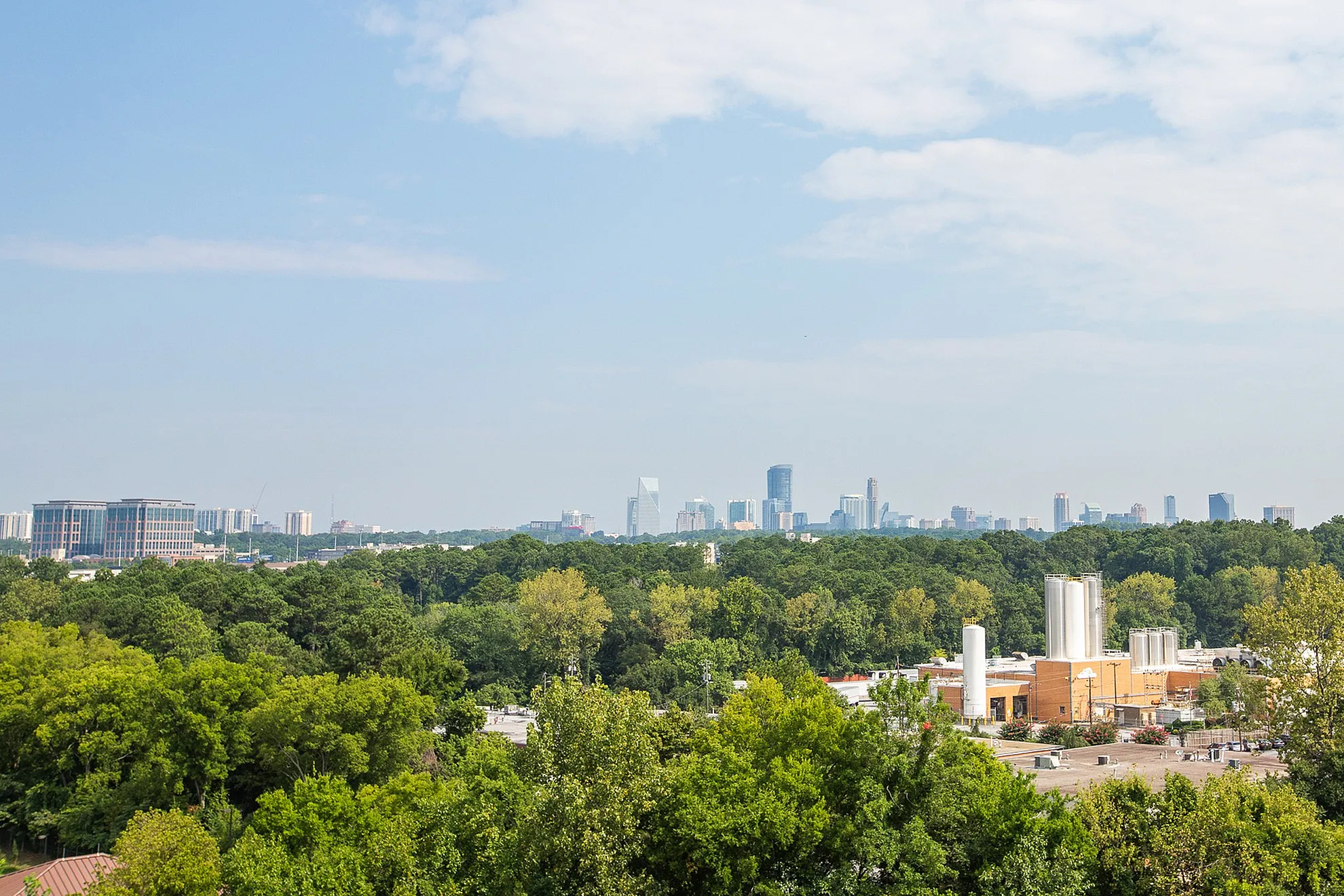 Breathtaking urban skyline view featuring lush greenery and modern high-rises under a clear blue sky.