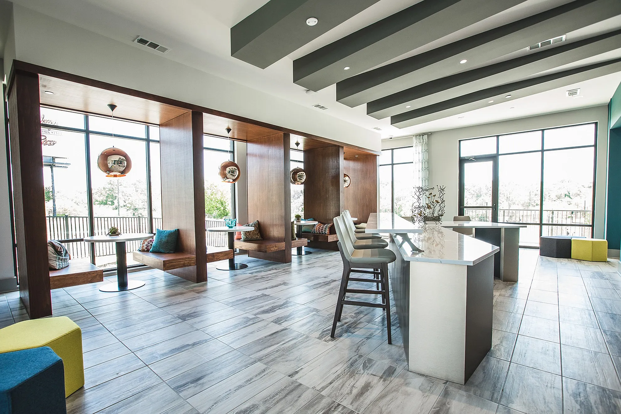 Contemporary lounge area with plush seating and modern decor, featuring elegant pendant lighting and large windows for natural light.