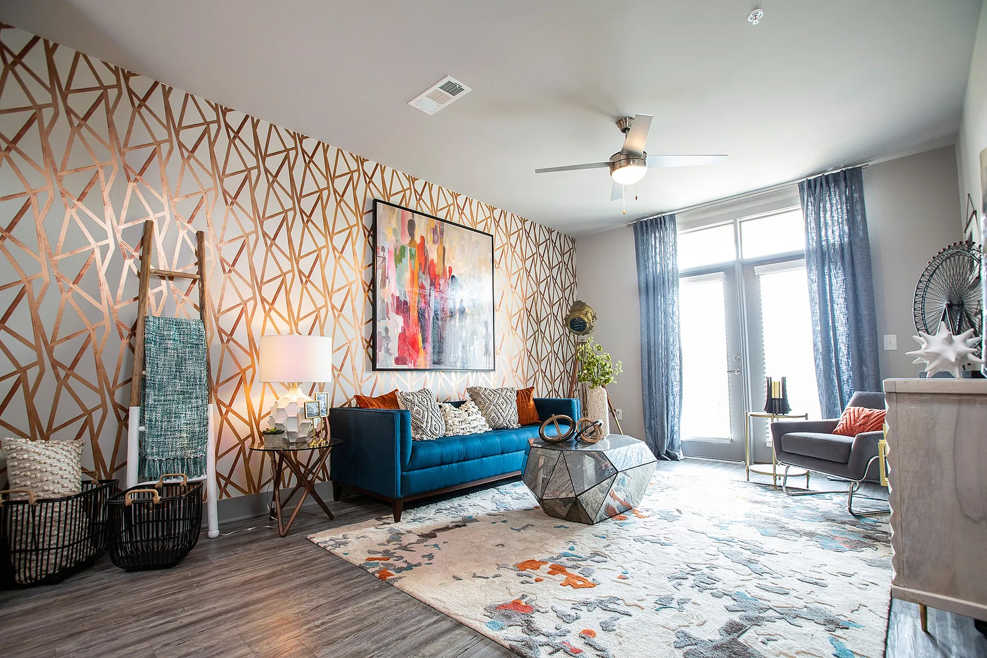 Vibrant living room with stylish geometric wall design, modern blue sofa, and chic decor accents.