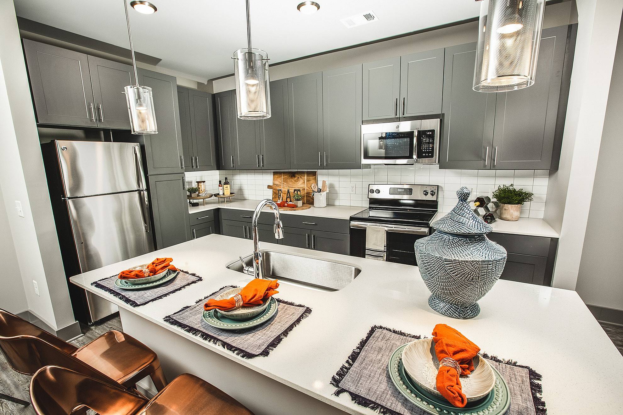 Modern kitchen with sleek dark cabinetry, stainless steel appliances, and a stylish island adorned with elegant table settings and contemporary decor.