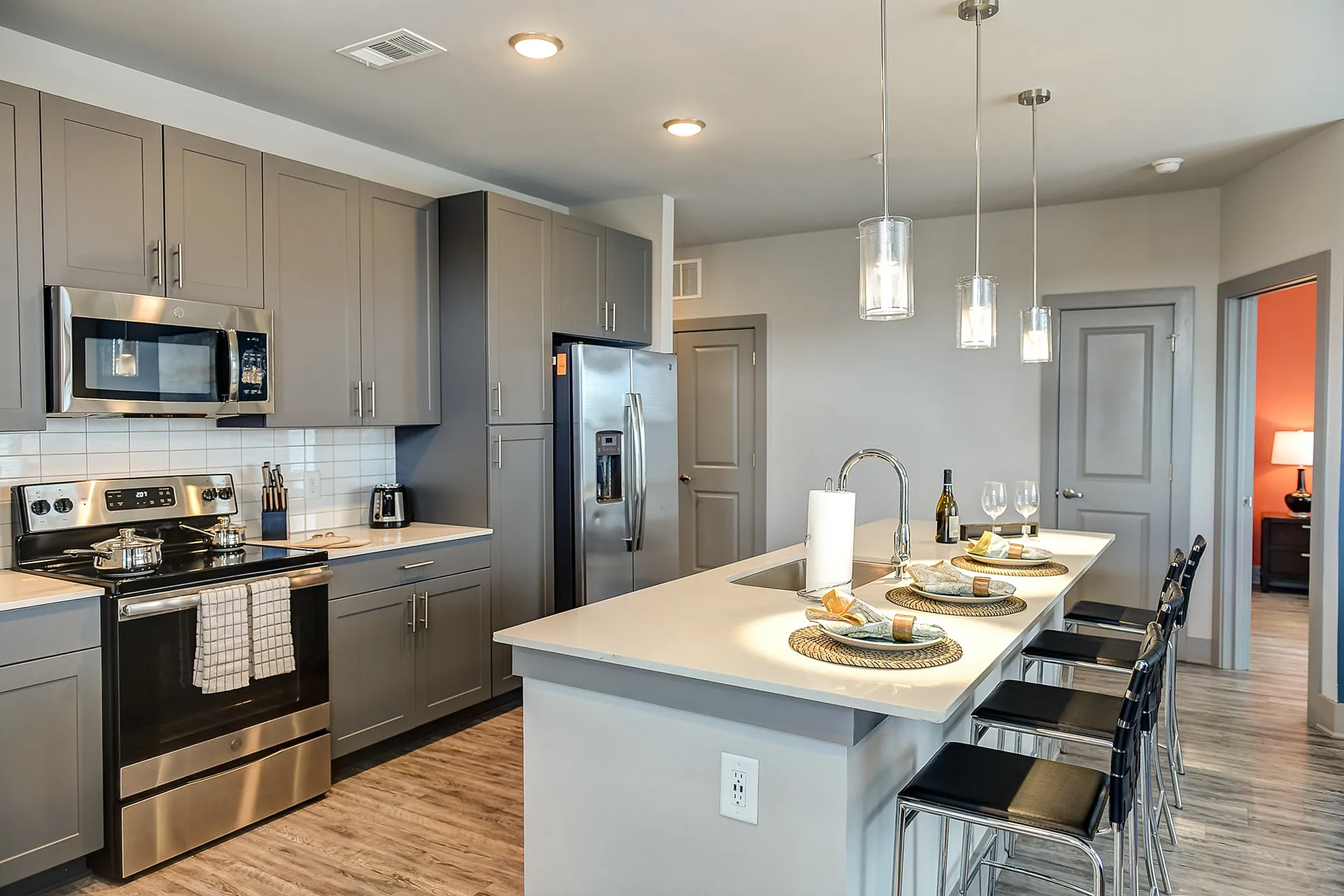Elegant modern kitchen with sleek gray cabinets, stainless steel appliances, and a stylish breakfast bar with pendant lighting.