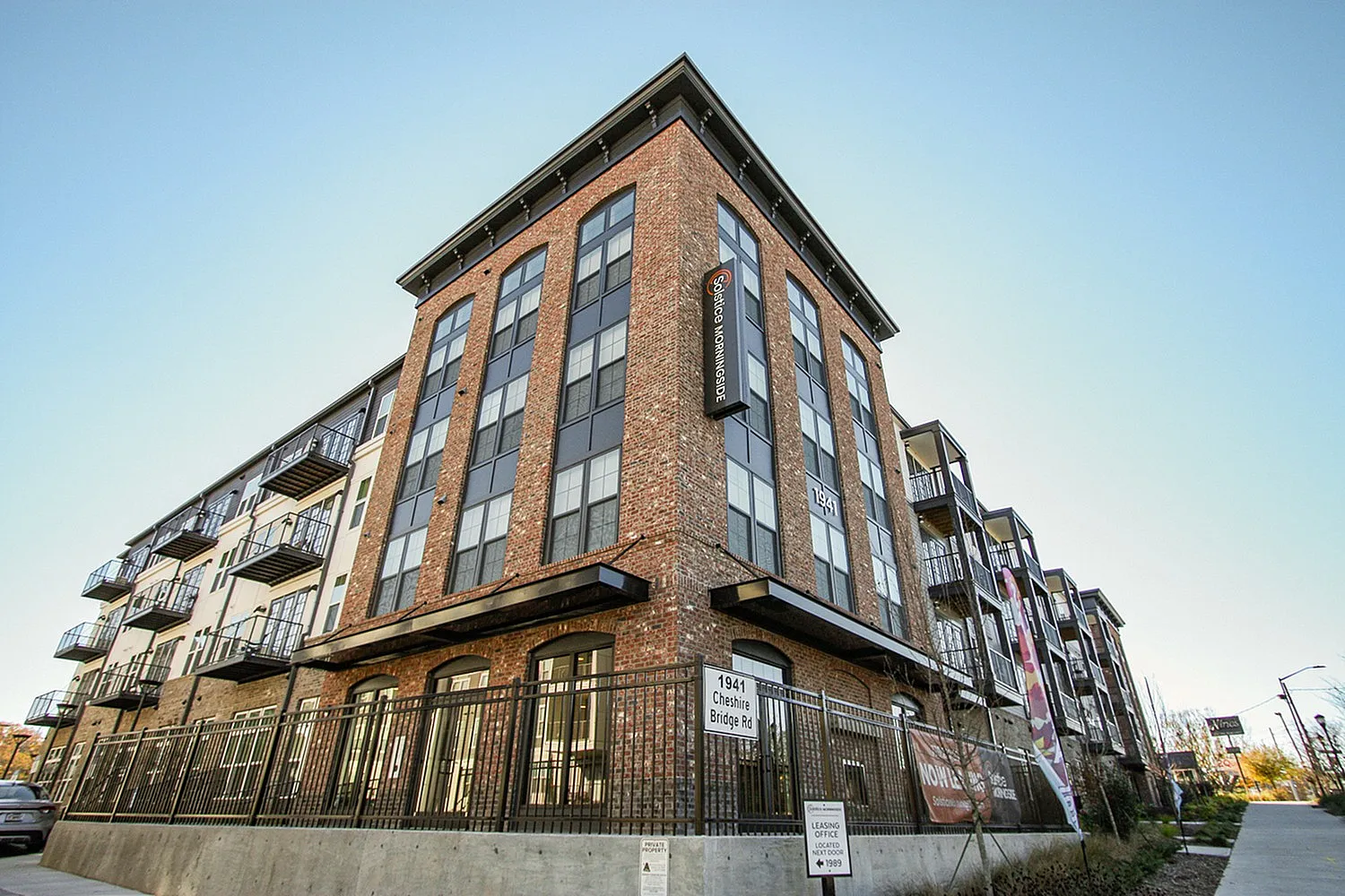 Modern brick apartment complex with large windows and balconies, featuring stylish urban design and strategic location.