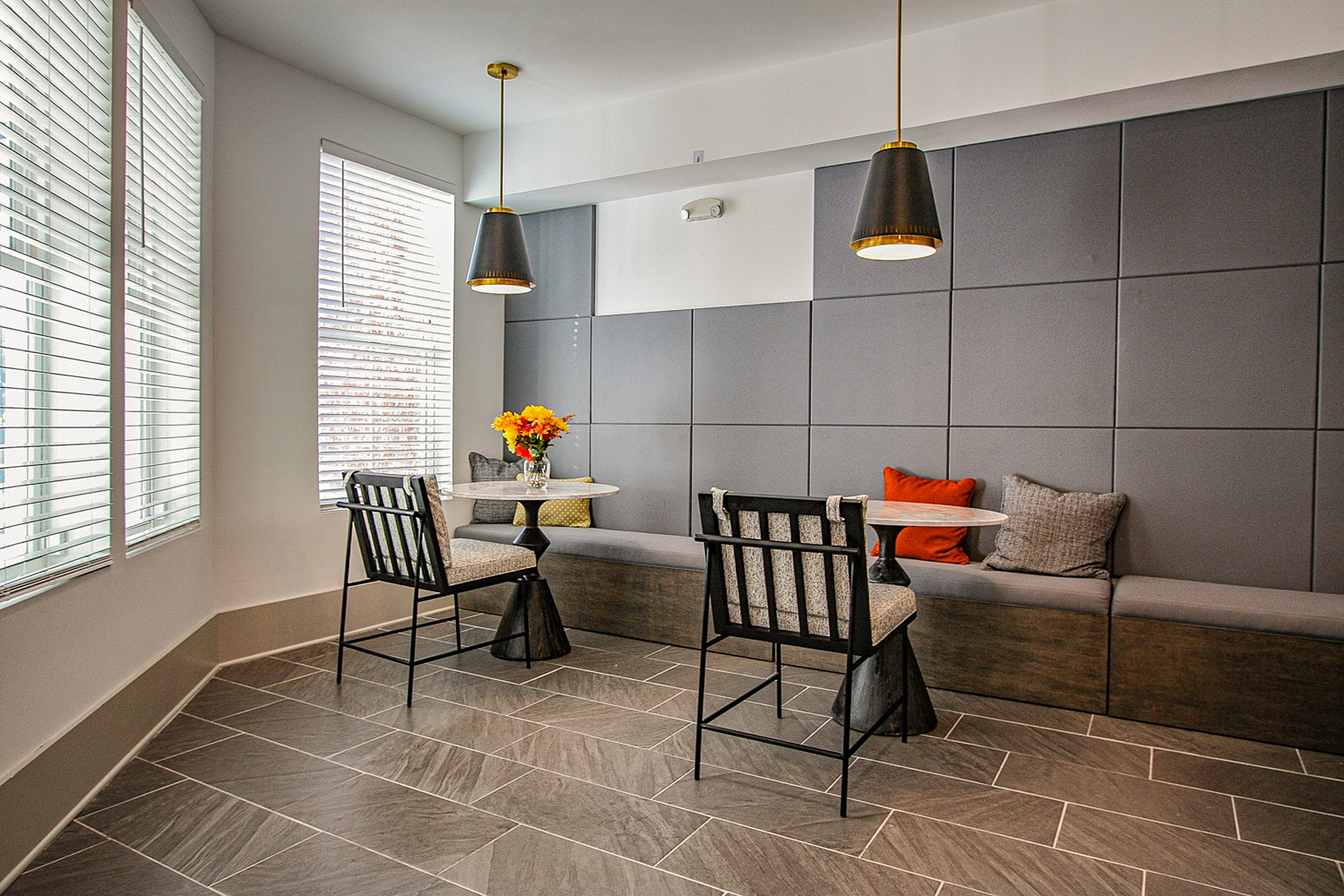 Elegant apartment lounge area with modern seating, ambient pendant lighting, and a stylish gray tiled floor.