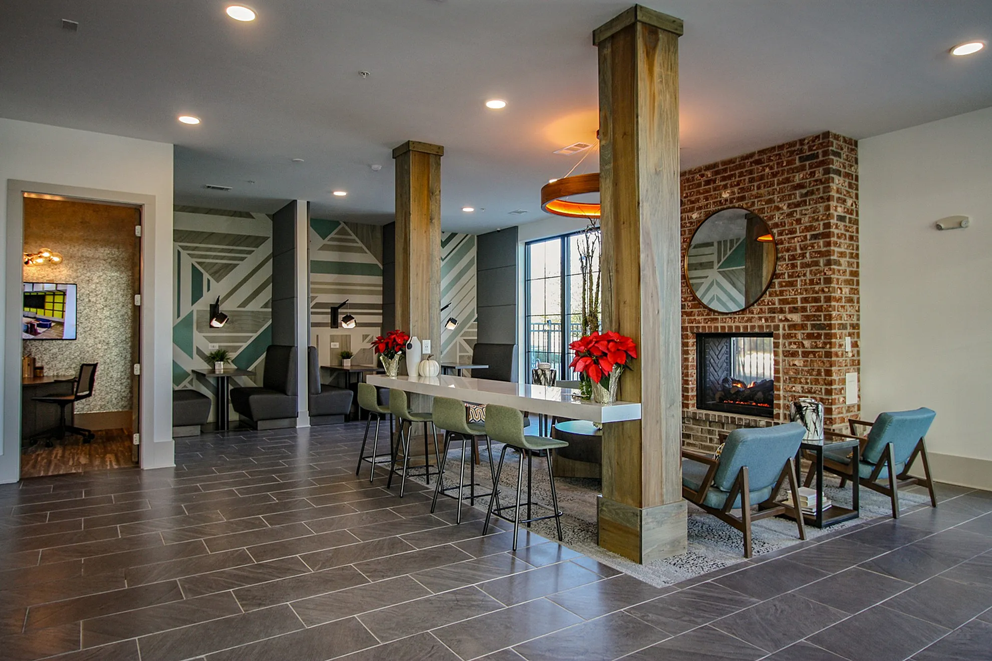 Chic and inviting communal area featuring modern seating, a brick fireplace, and stylish decor with geometric wall art and elegant lighting.
