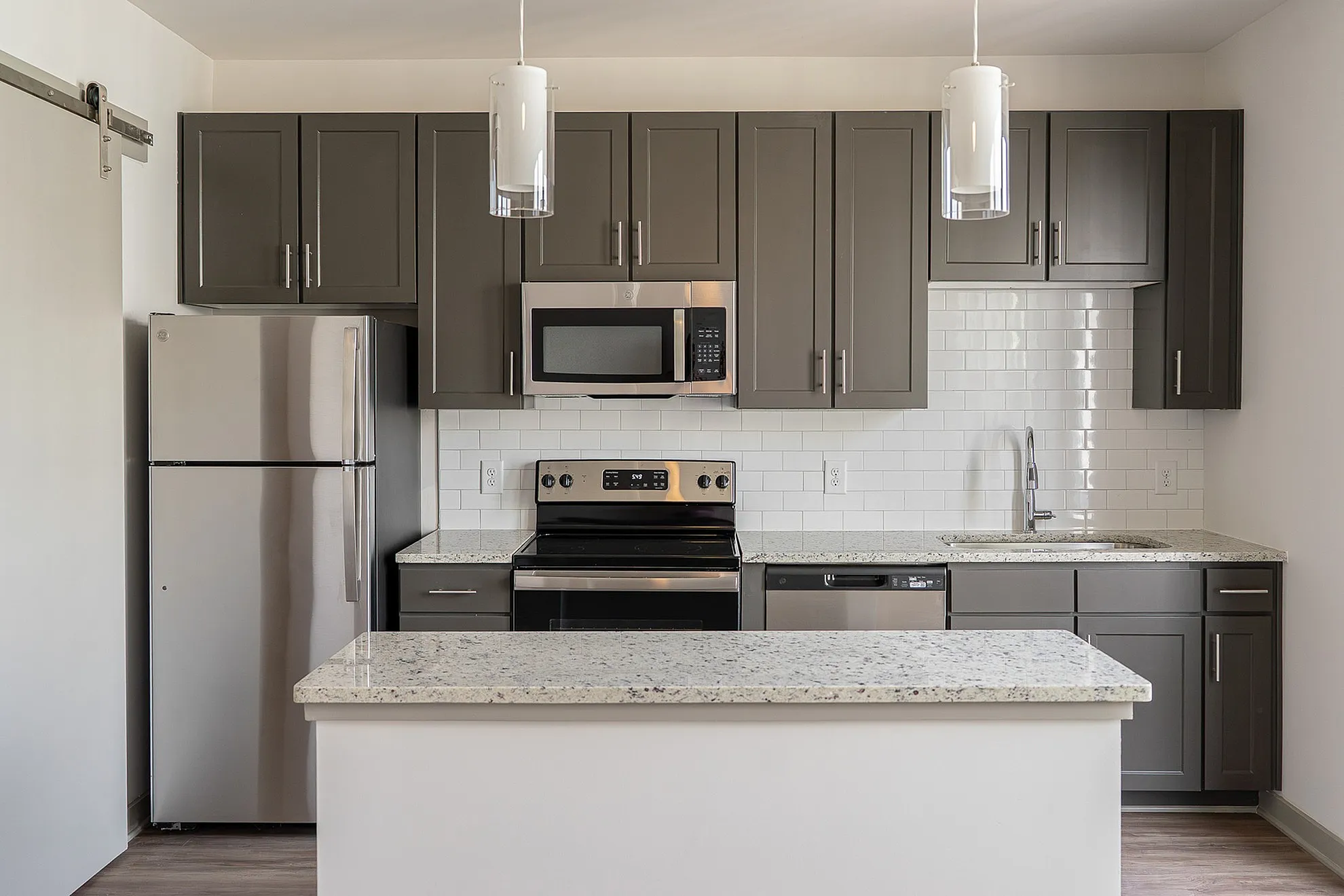Modern kitchen with sleek stainless steel appliances, elegant dark cabinets, and a spacious granite countertop island, offering a blend of style and functionality.