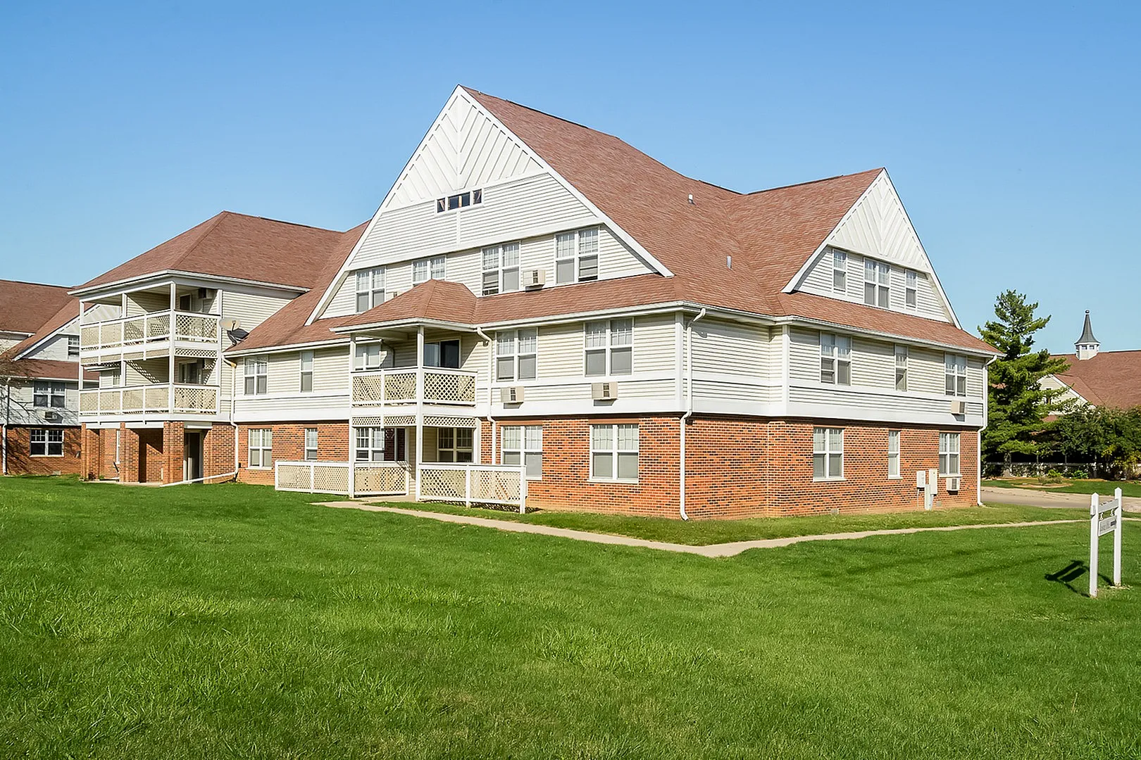 Charming multi-story apartment building with a spacious exterior and inviting balconies, set in lush green surroundings.