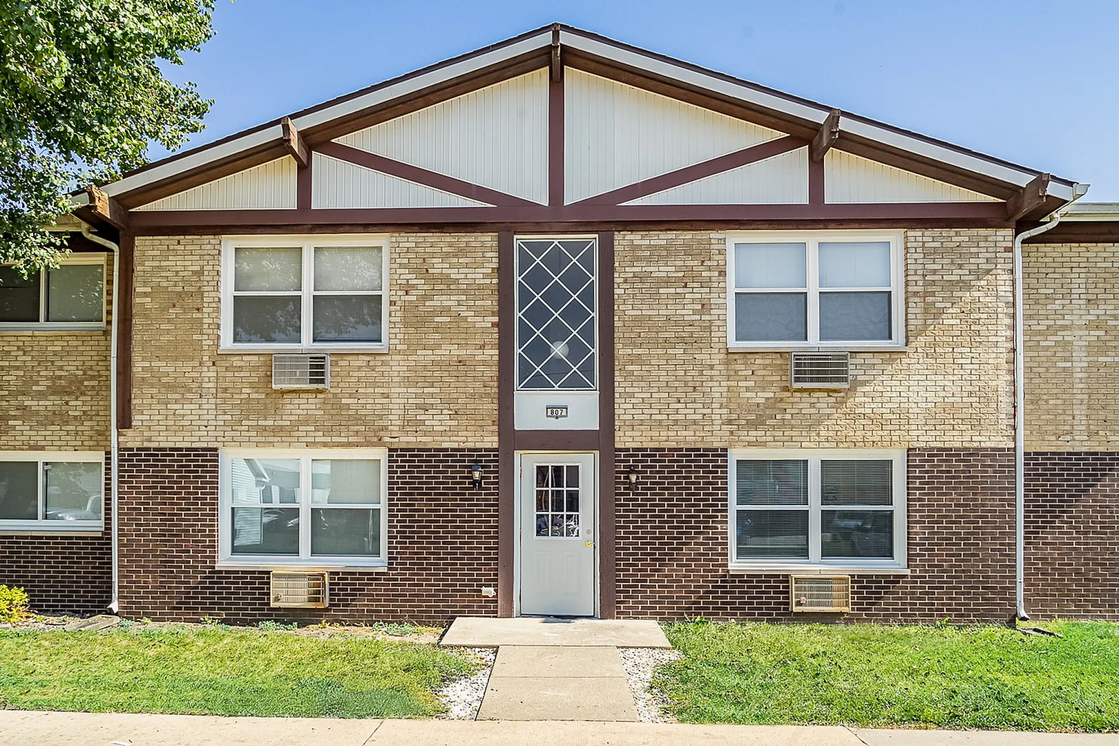 Inviting brick apartment complex with large windows and charming architectural details, ideal for comfortable living.