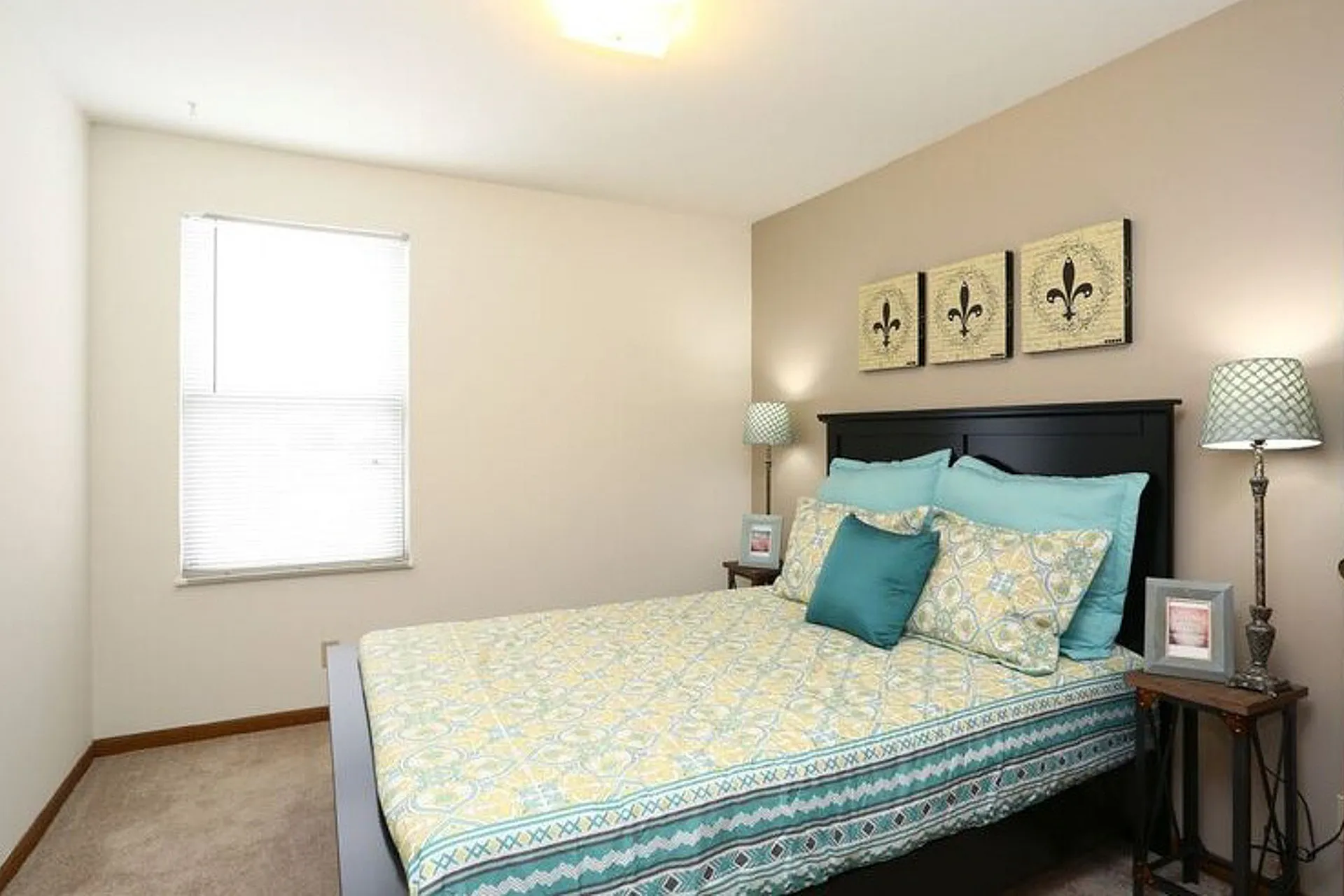 Cozy bedroom featuring a plush bed with patterned bedding, soft lighting from elegant table lamps, and stylish wall art for a touch of sophistication.