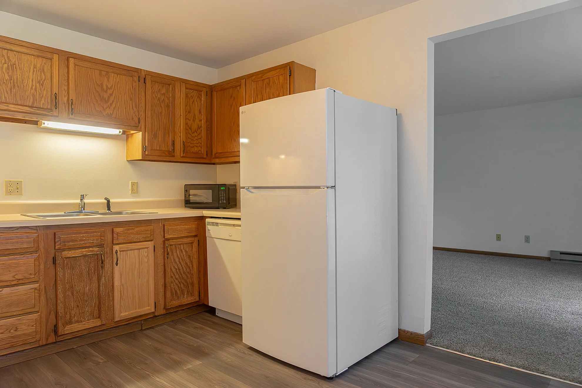 Inviting kitchen with classic wooden cabinetry, modern refrigerator, and spacious countertops for convenient meal preparation.