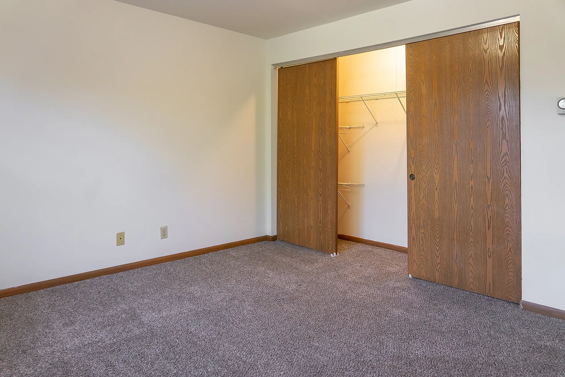 Charming bedroom with plush carpet and a spacious closet featuring sliding wooden doors.