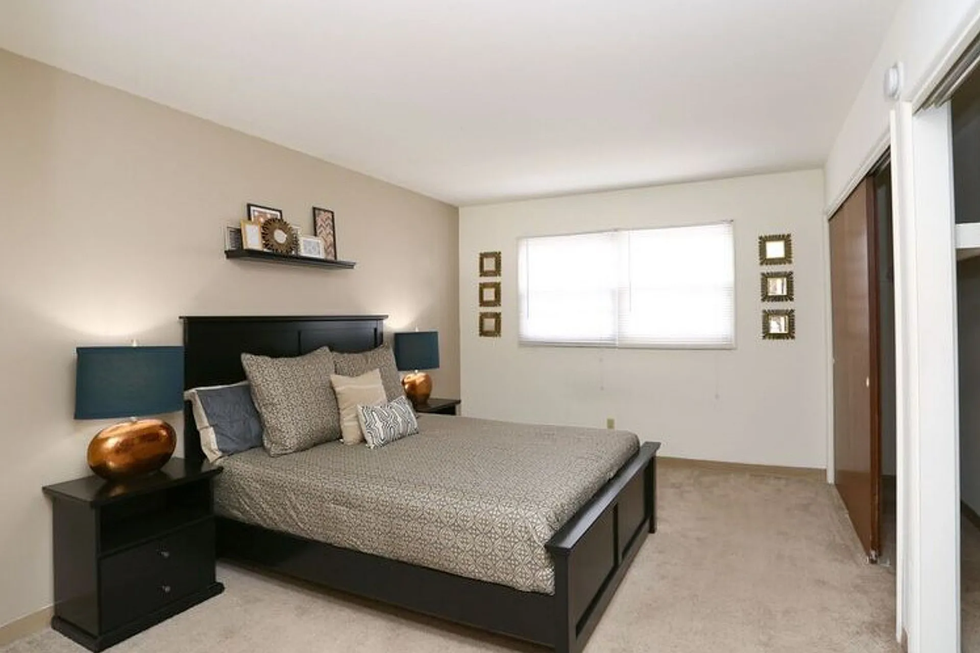Inviting bedroom featuring a cozy queen-sized bed with elegant decor, soft carpeting, and natural light from a large window.
