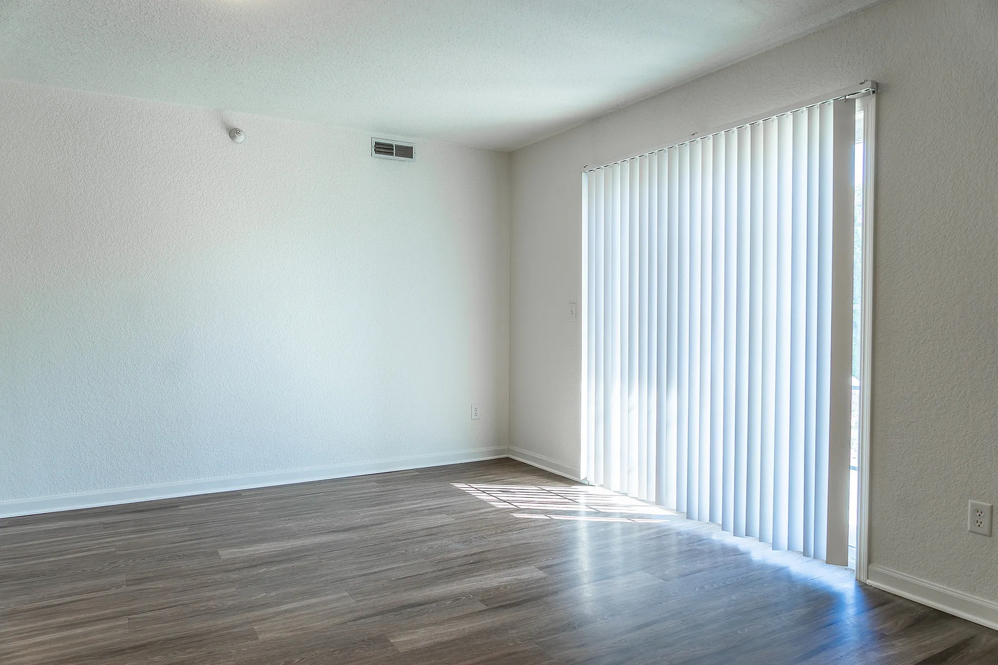 Bright and airy living space with elegant wood flooring and floor-to-ceiling blinds, perfect for natural light.