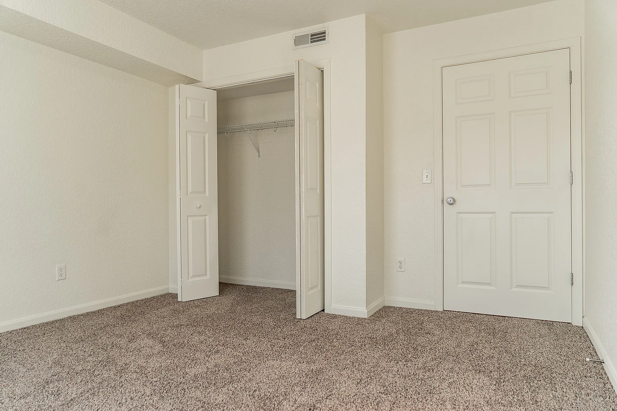 Bright bedroom with plush carpet, spacious closet, and elegant neutral tones for a cozy ambiance.