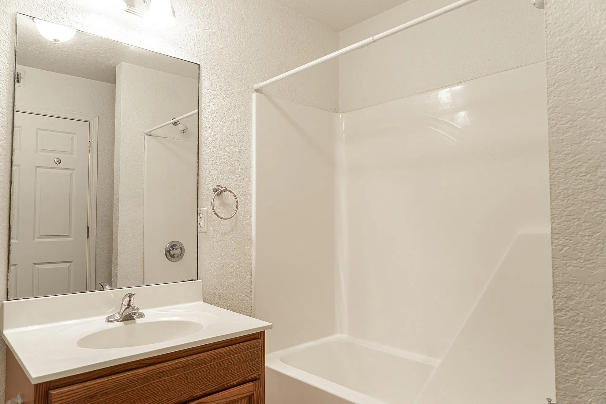 Elegant bathroom with a pristine bathtub, large mirror, and sleek vanity, showcasing modern fixtures and a serene atmosphere.