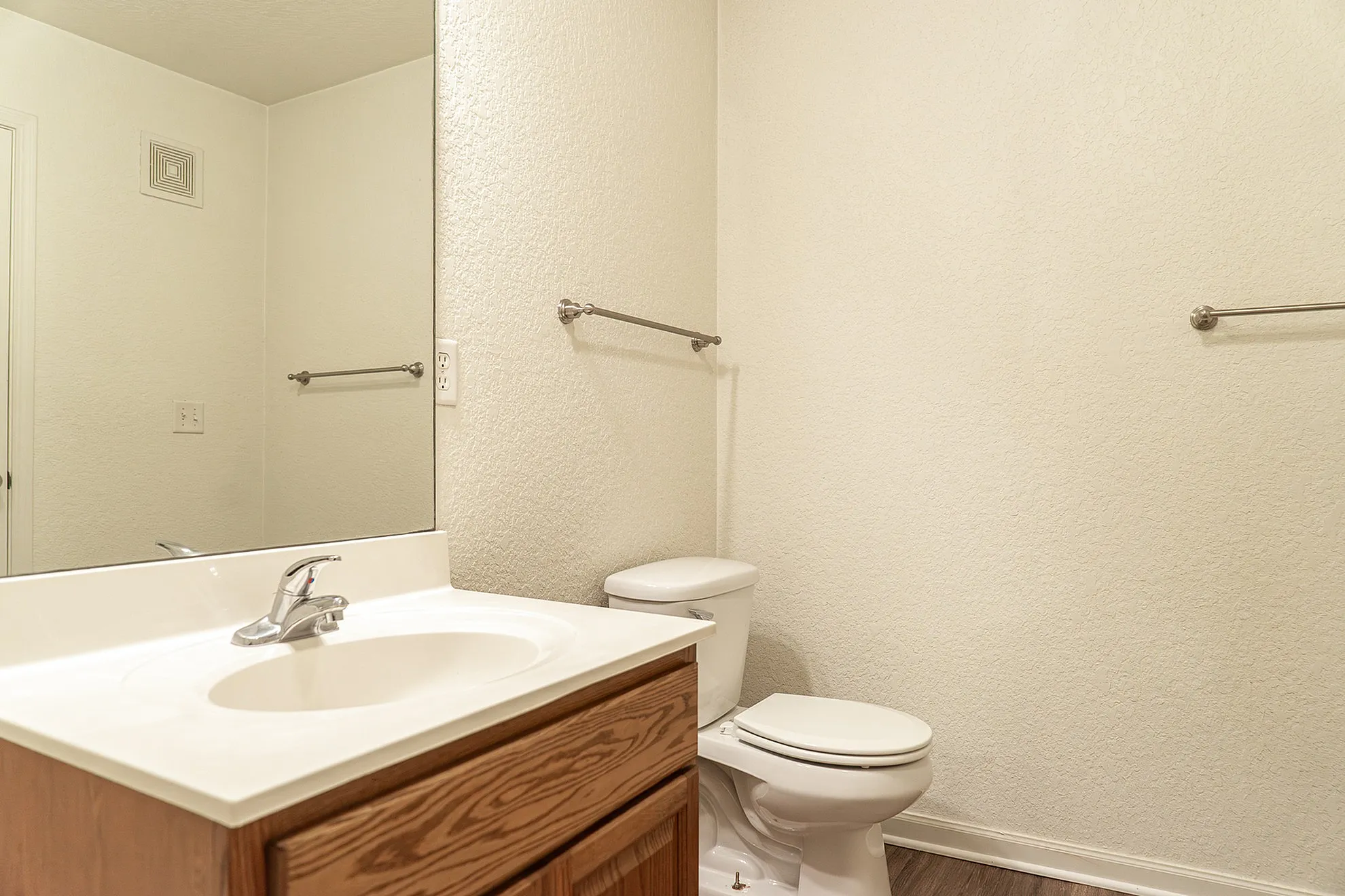 Bright and modern bathroom with sleek surfaces, featuring a large mirror and refined wood cabinetry for a sophisticated touch.