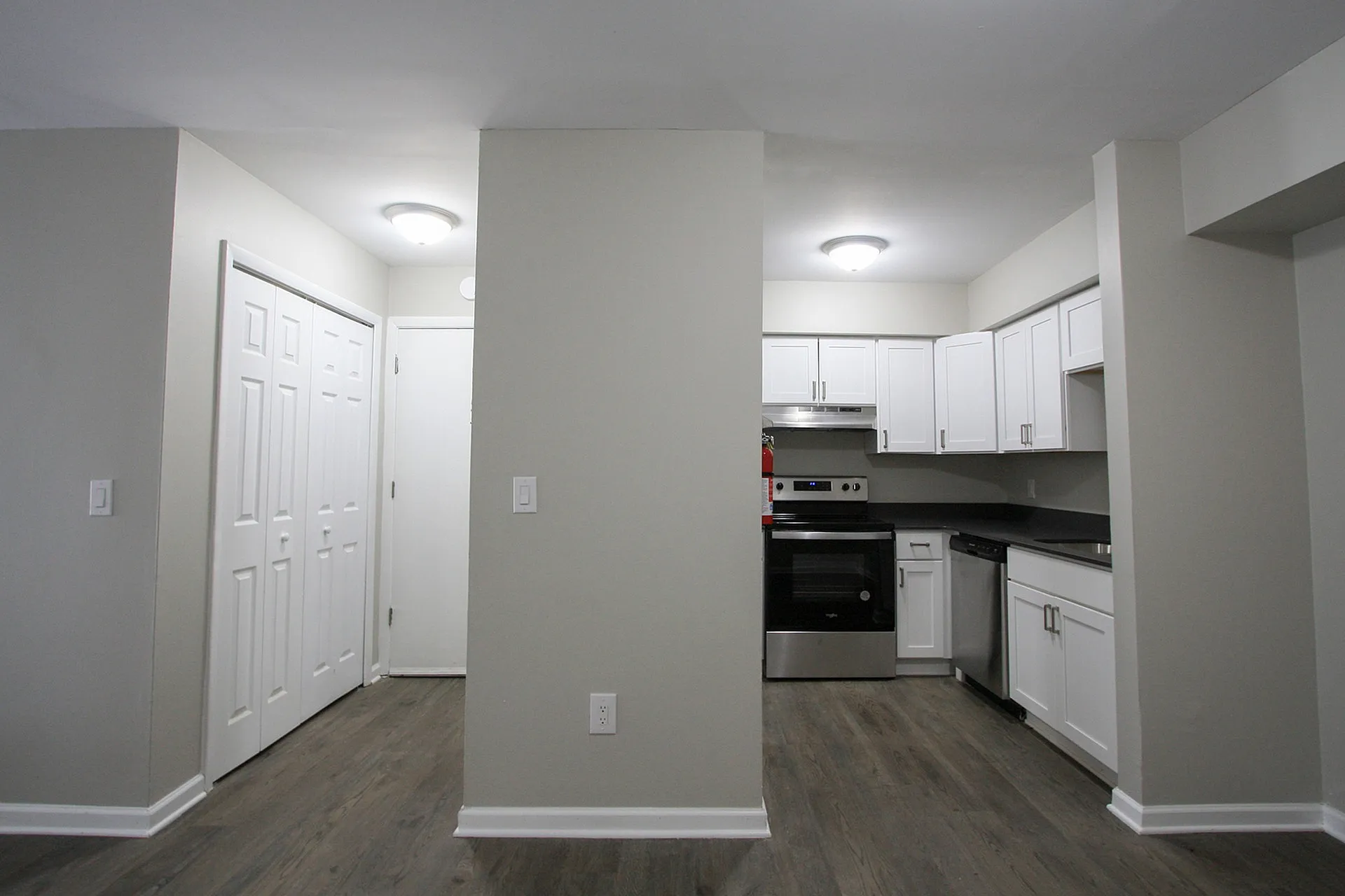 Modern kitchen with sleek white cabinets, stainless steel appliances, and elegant wood flooring in a contemporary open space.