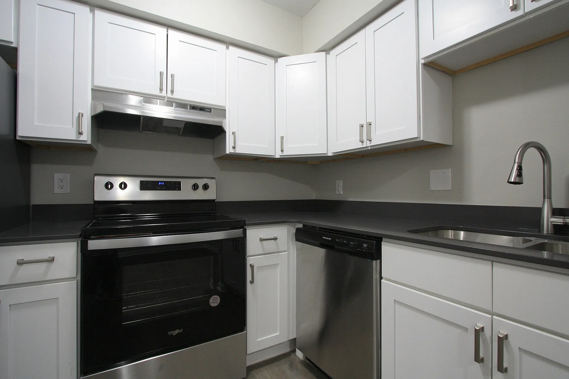 Modern kitchen with sleek stainless steel appliances, elegant white cabinetry, and polished dark countertops.