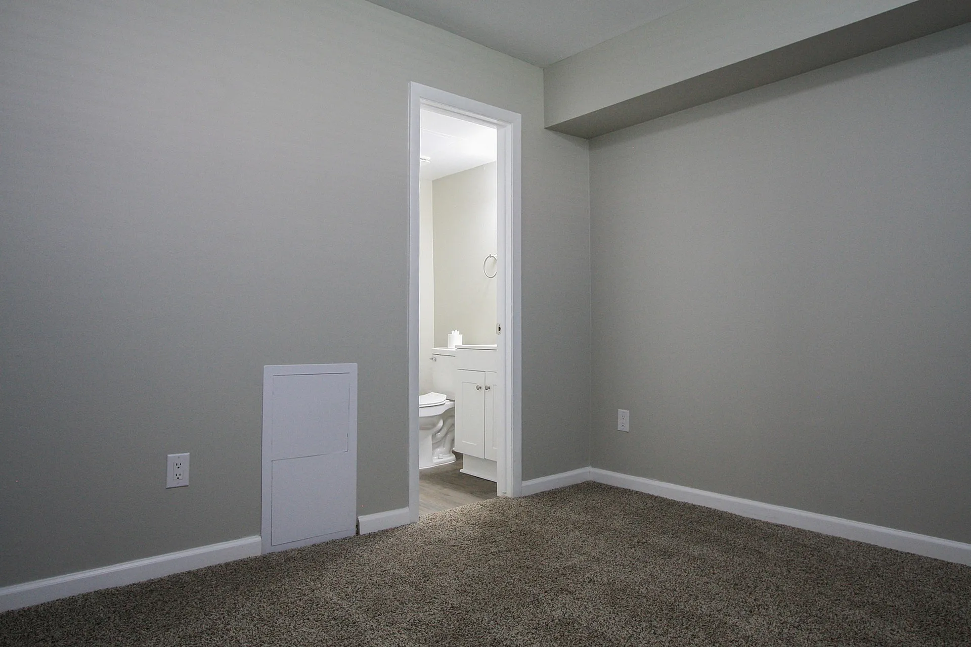 Inviting room with plush carpet, neutral walls, and convenient en-suite bathroom access.