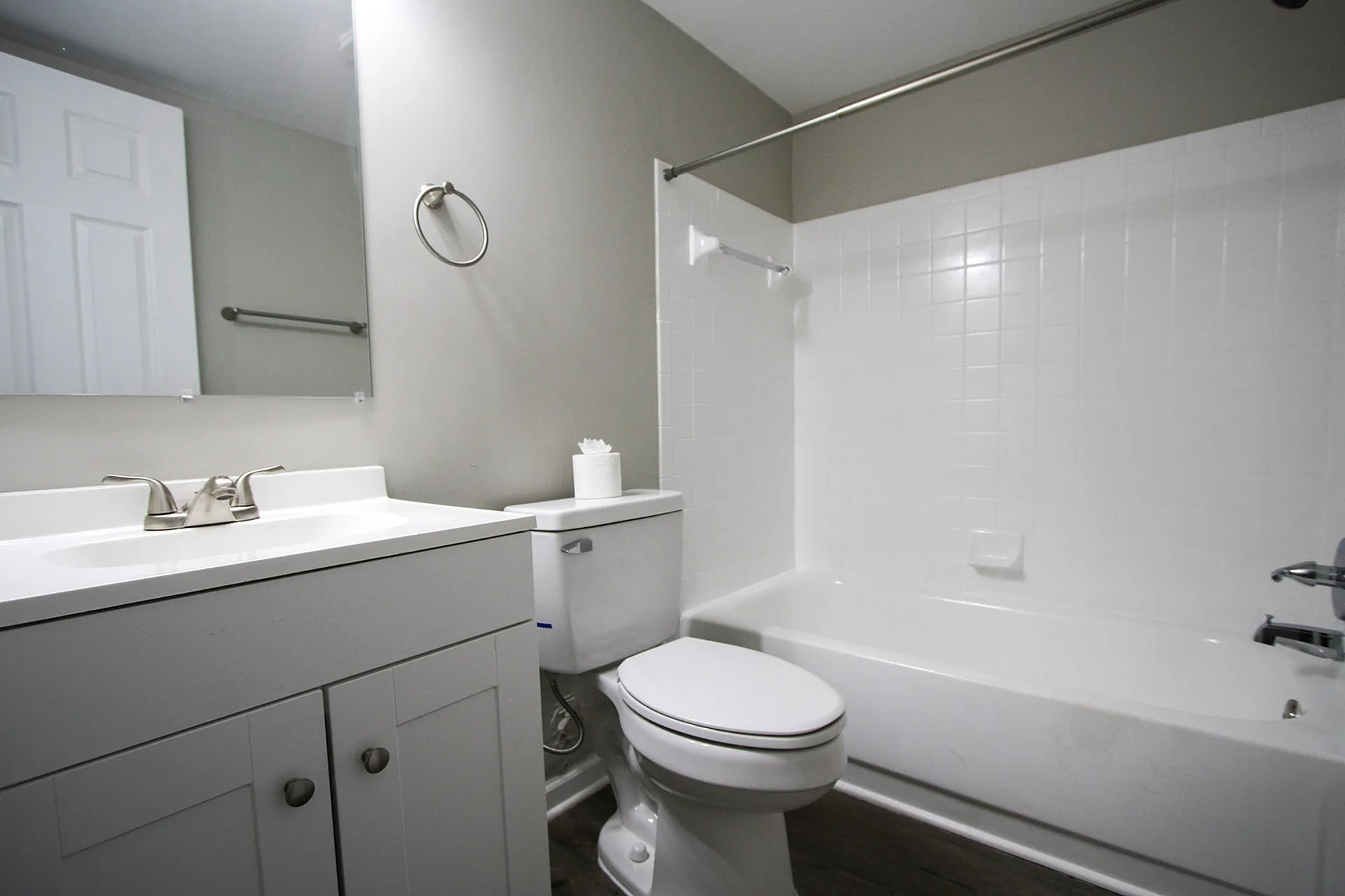 Bright and modern bathroom featuring elegant white fixtures, a sleek vanity with ample storage, and a pristine bathtub with classic tiling.