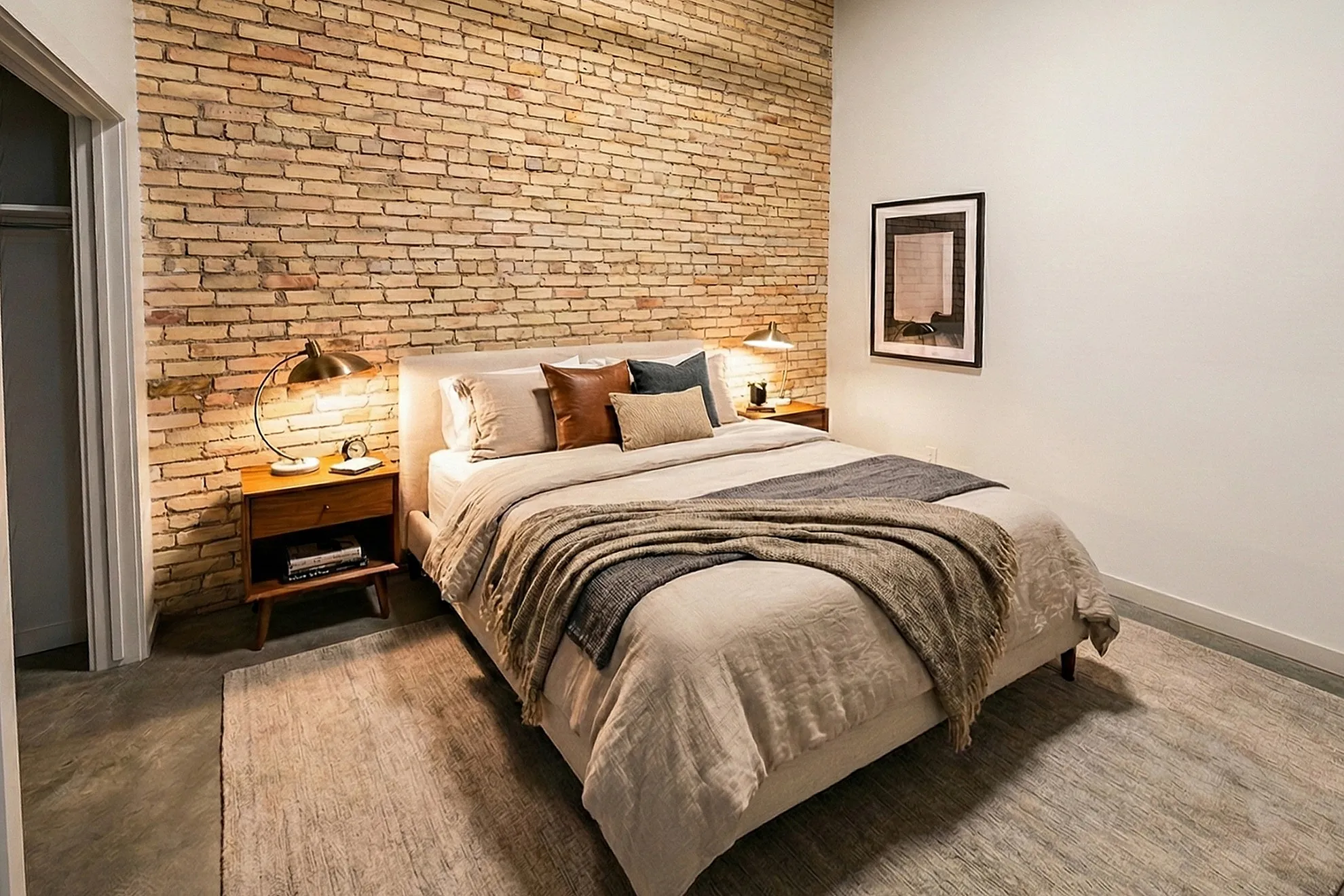 Cozy bedroom with exposed brick wall, soft lighting, and stylish modern decor.