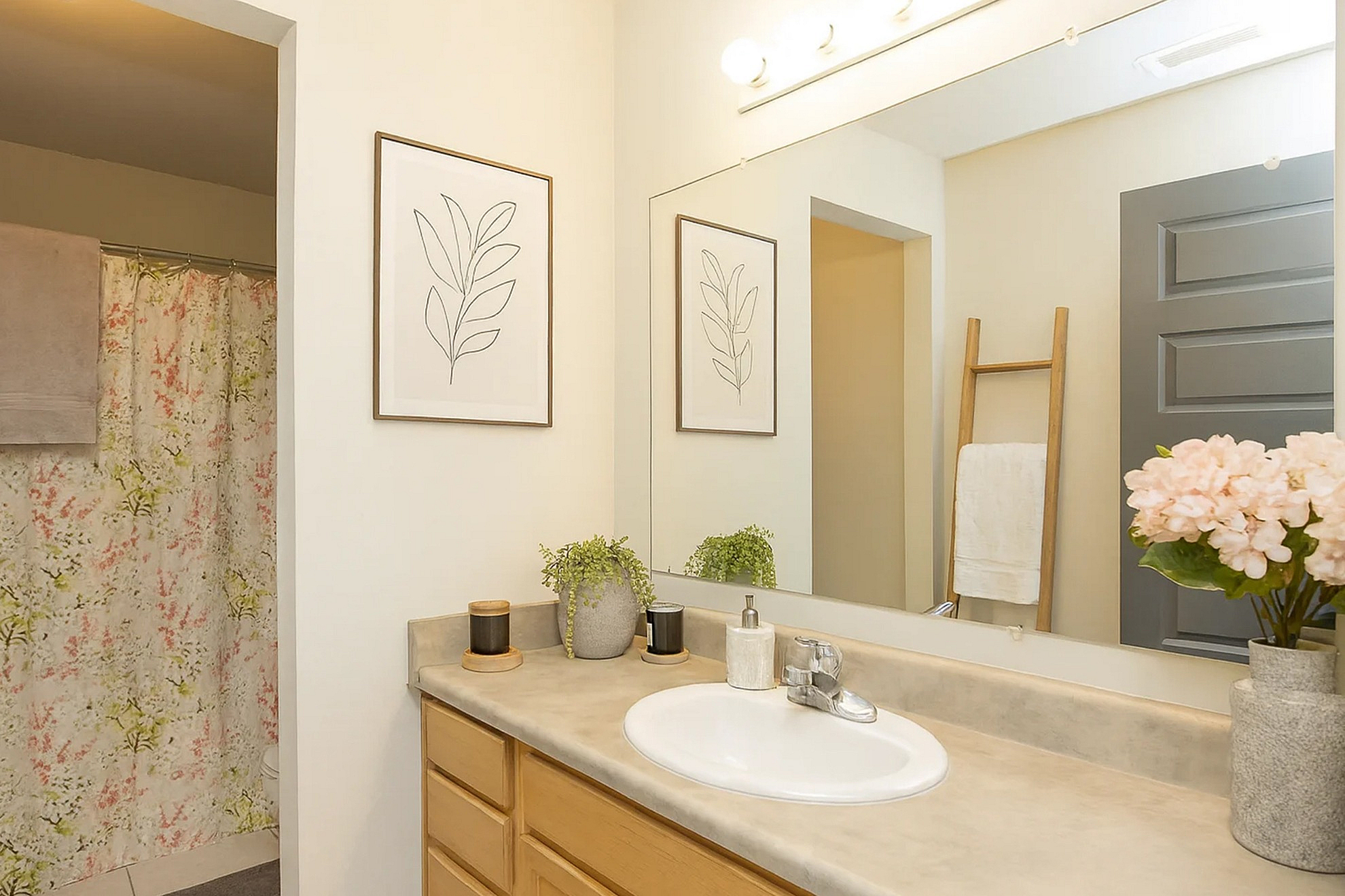 Modern bathroom with elegant decor, featuring a stylish vanity, chic framed artwork, and a vibrant floral shower curtain.