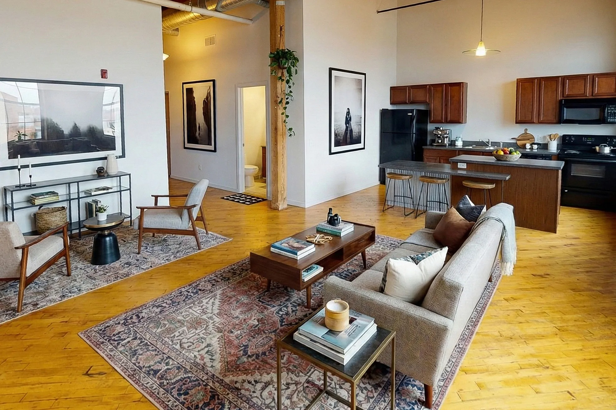 Chic open-concept living area with elegant hardwood floors, modern kitchen, and cozy seating arrangement.