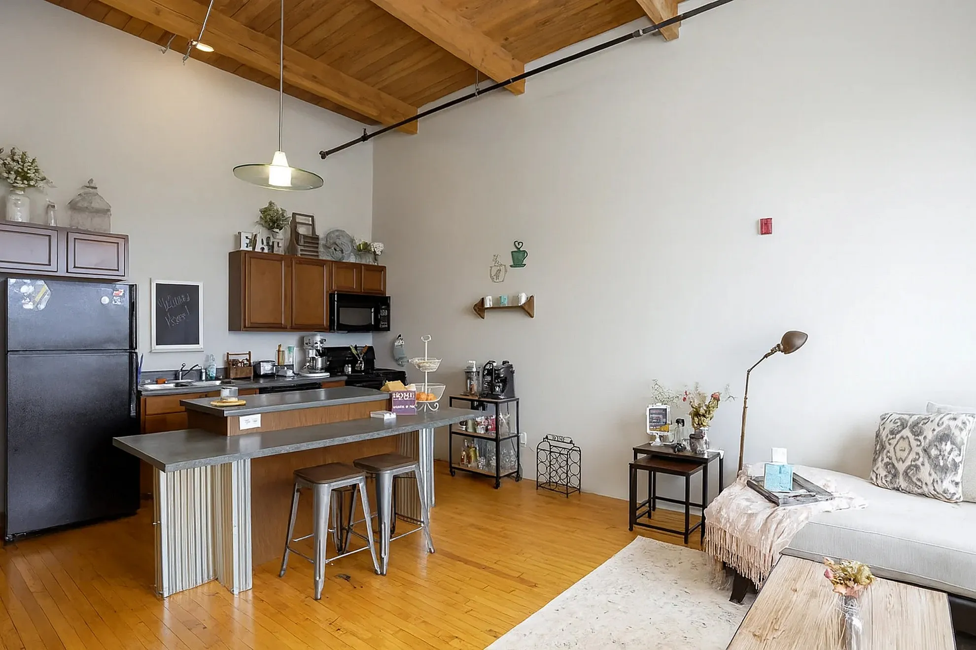 Chic open-concept living area with a cozy kitchen, featuring wooden beams and modern decor.