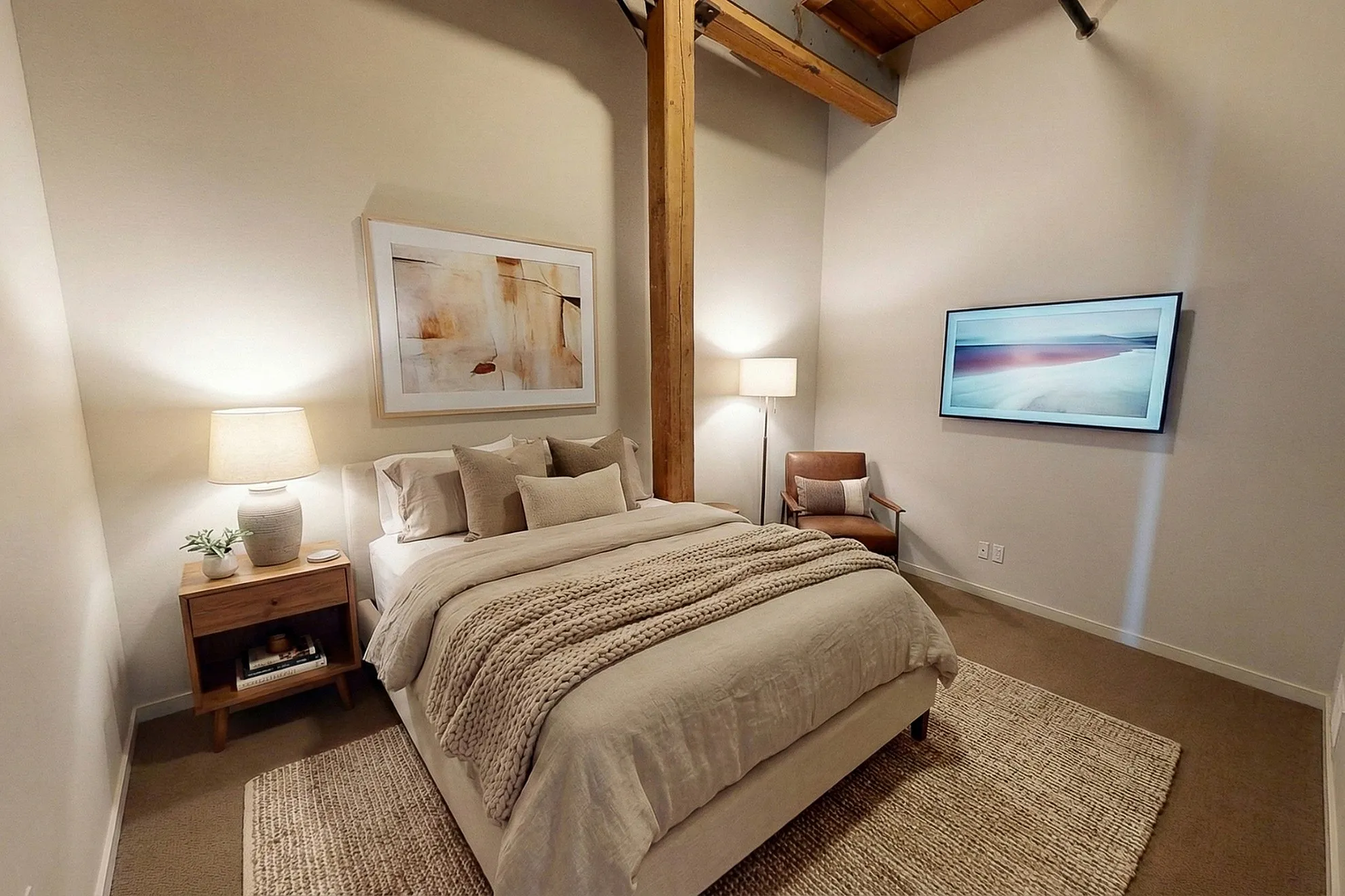 Cozy bedroom with warm lighting, featuring a comfortable bed, stylish artwork, and modern decor in a chic apartment setting.