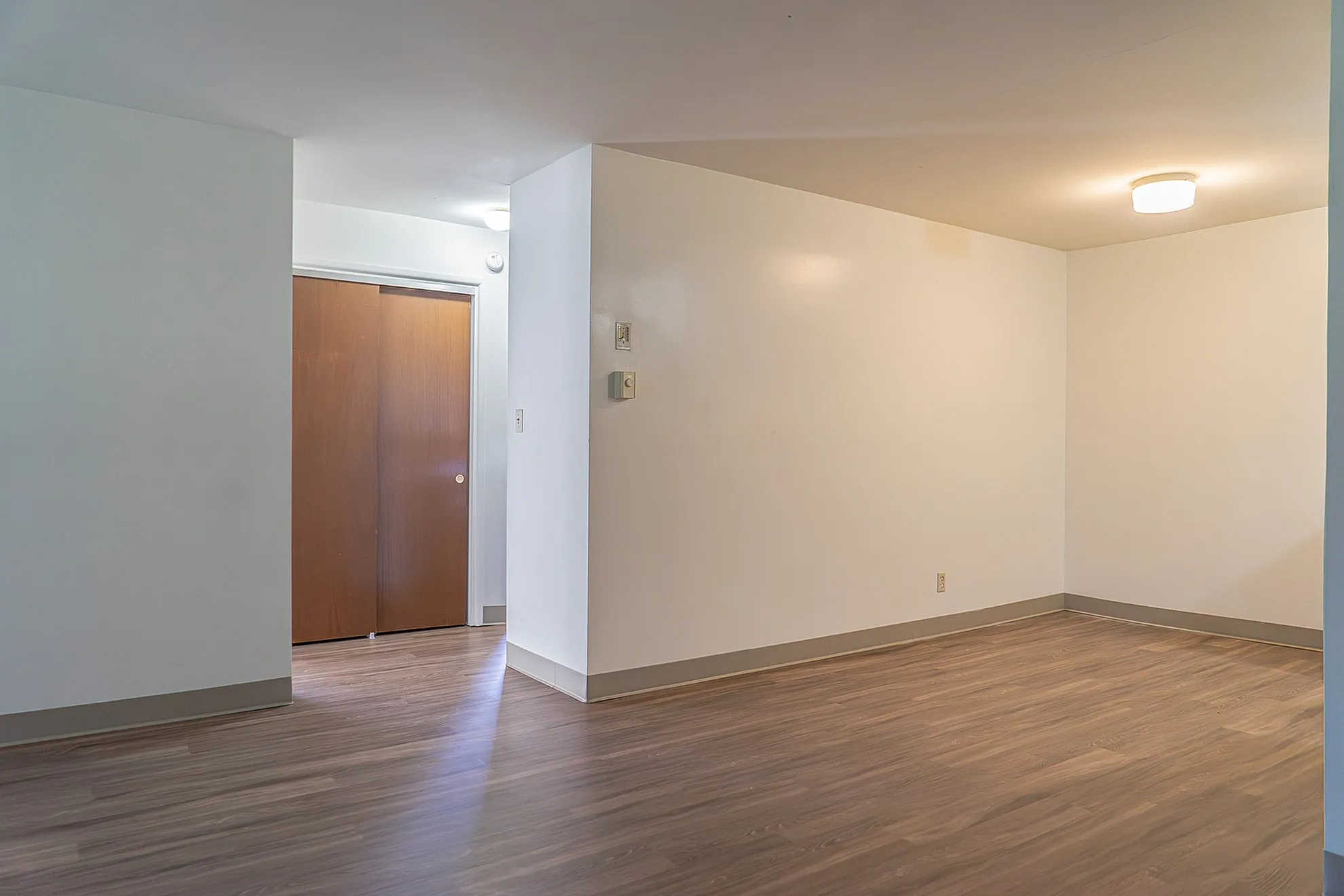 Bright and inviting open-concept space with sleek wooden floors, perfect for customization with modern decor.