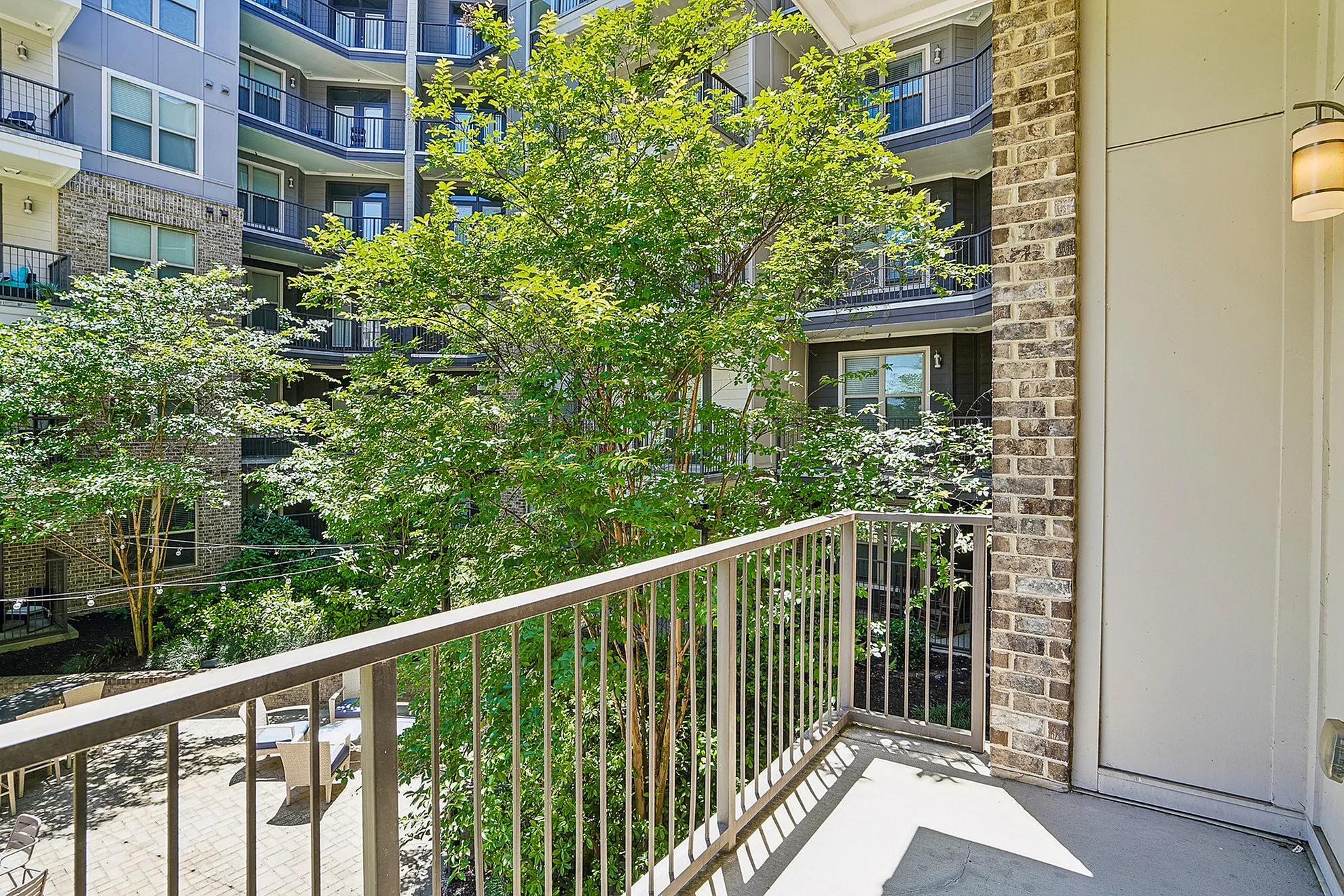 Charming apartment balcony with lush greenery and modern building view, perfect for relaxing outdoors.