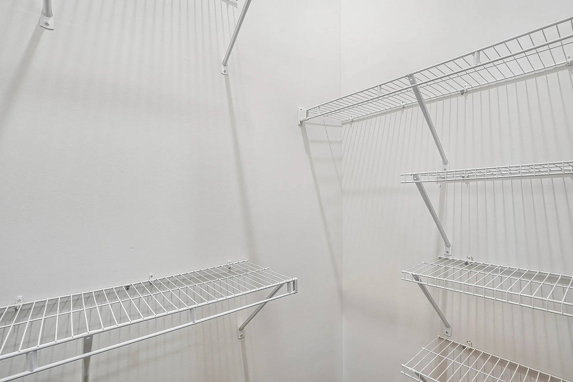 Bright and spacious walk-in closet with adjustable wire shelving, perfect for organized storage.