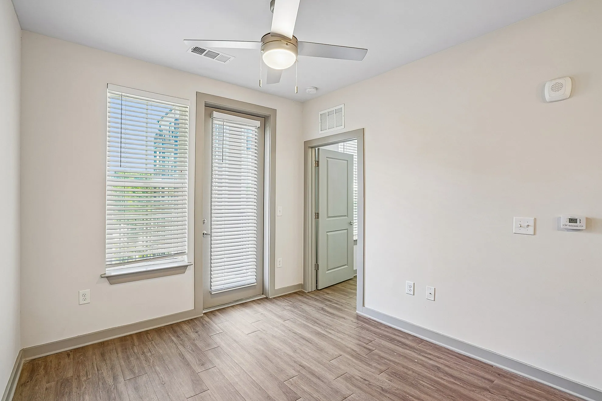 Bright room with large windows and wooden flooring, offering a modern and inviting atmosphere in a well-designed apartment.