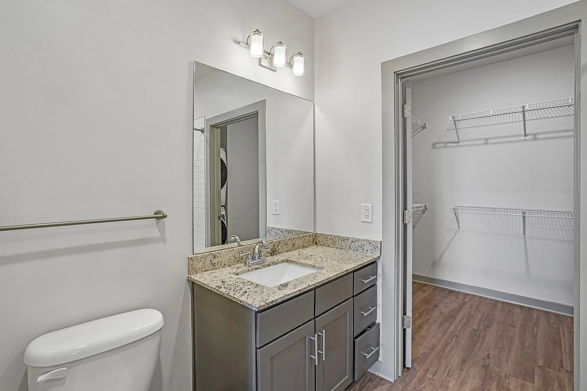 Modern bathroom with elegant granite countertop, sleek vanity, and spacious walk-in closet.