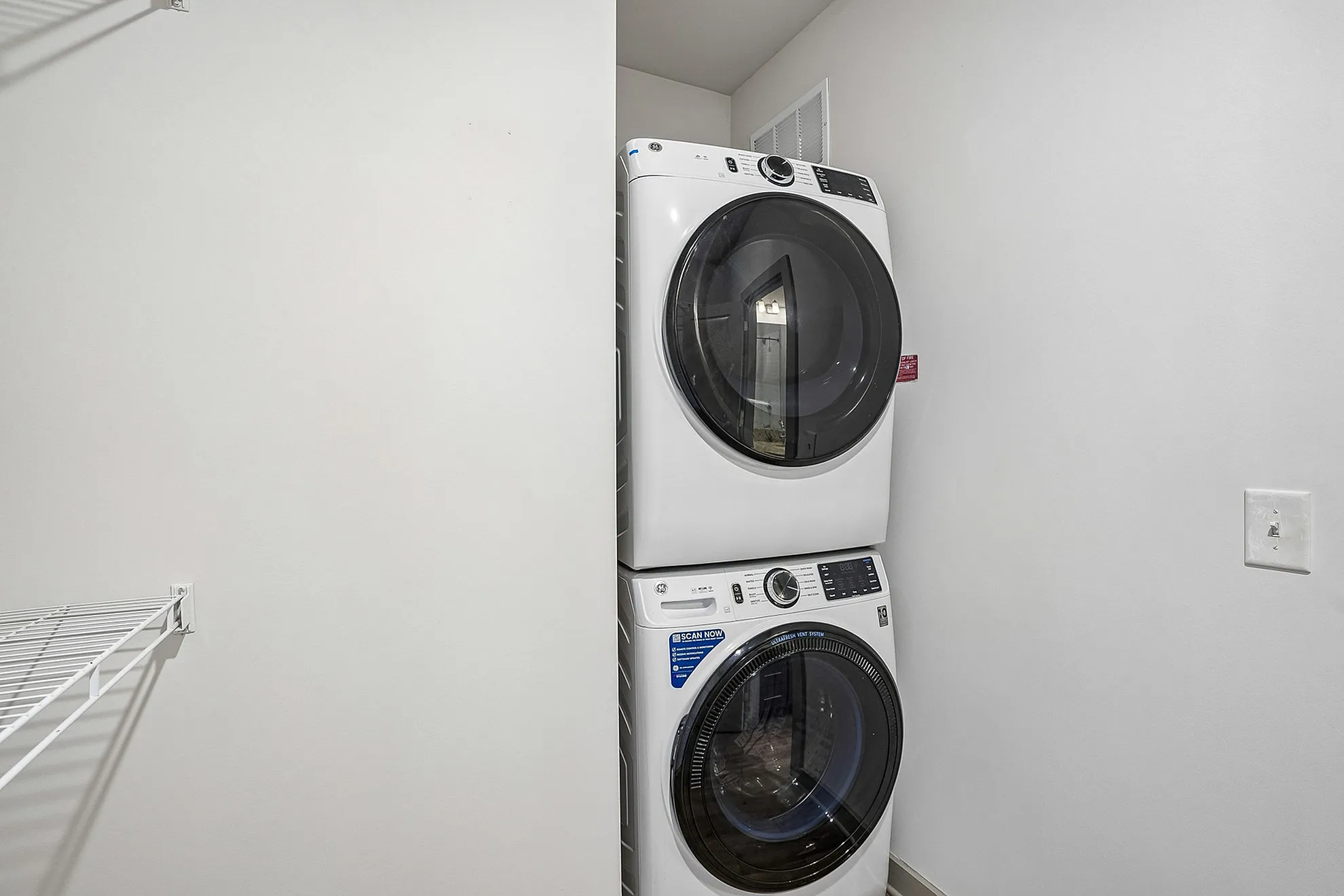 Convenient in-unit laundry area featuring a sleek stacked washer and dryer, perfect for modern living.