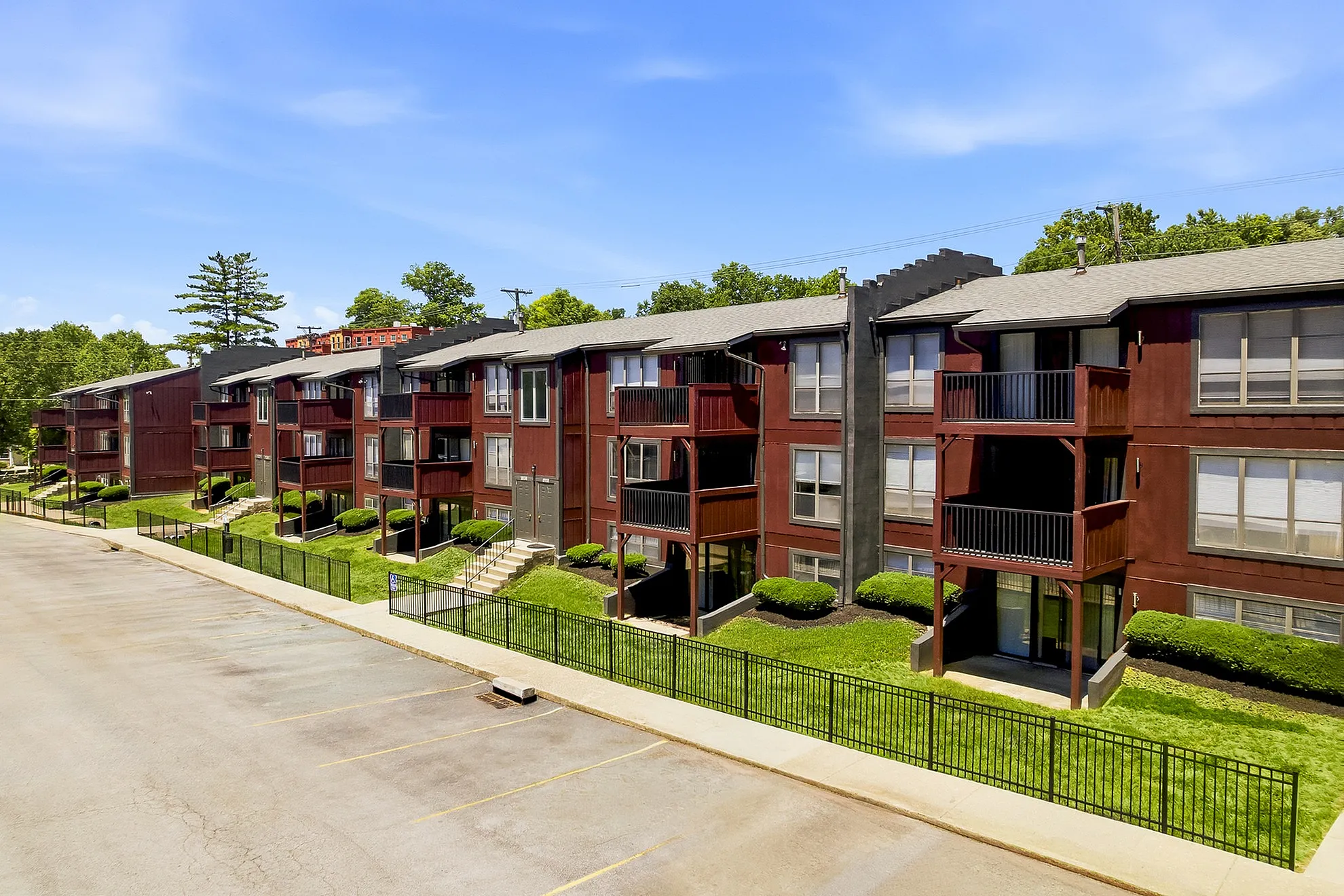 Charming brown apartment complex with private balconies and lush green surroundings, perfect for modern living.