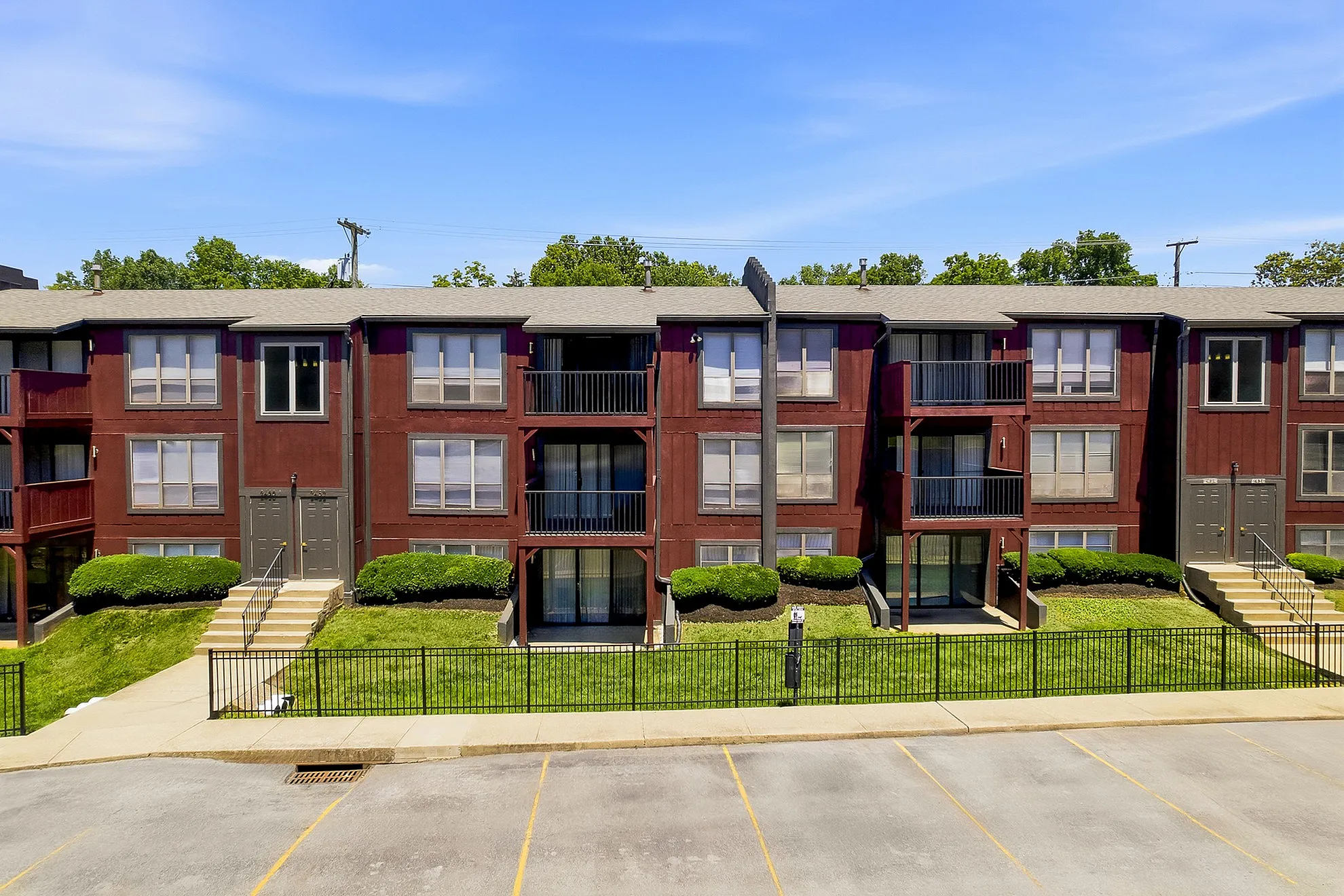Charming red brick apartment complex with private balconies and lush landscaping, ideal for modern living.