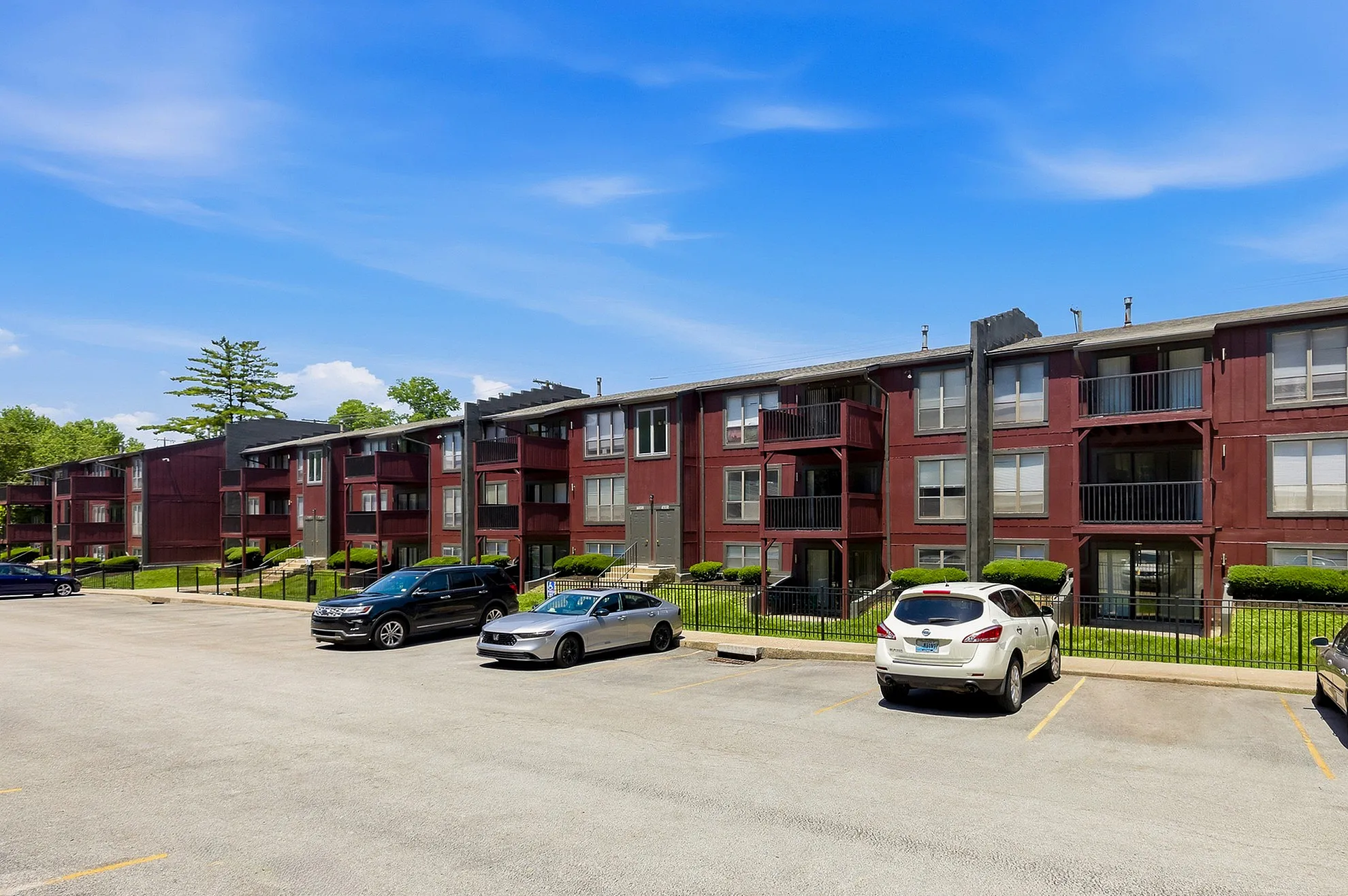 Charming apartment complex with spacious balconies and ample parking, set against a clear blue sky.