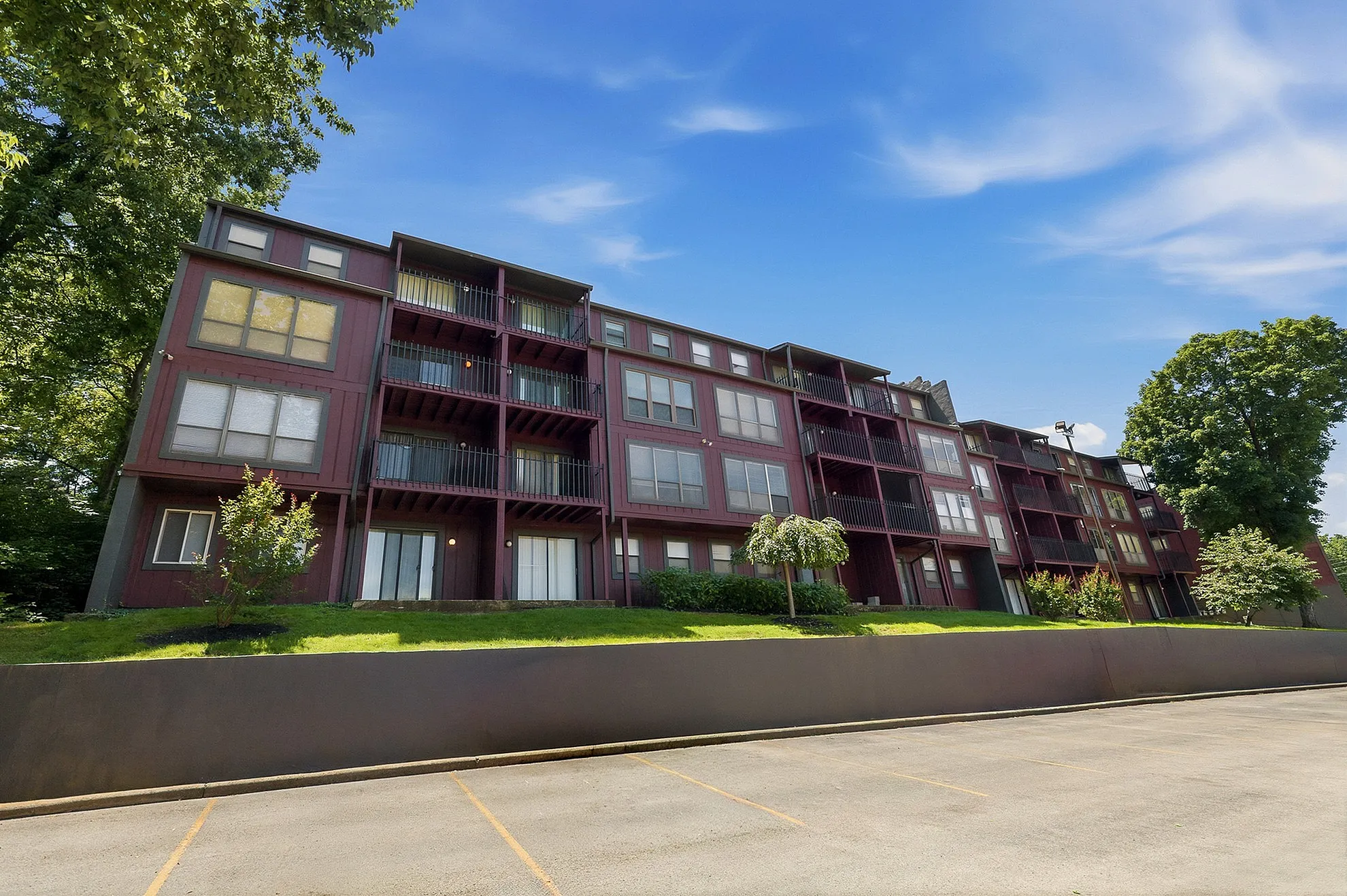 Charming multi-level apartment complex with spacious balconies, nestled in a green, serene setting under a bright blue sky.