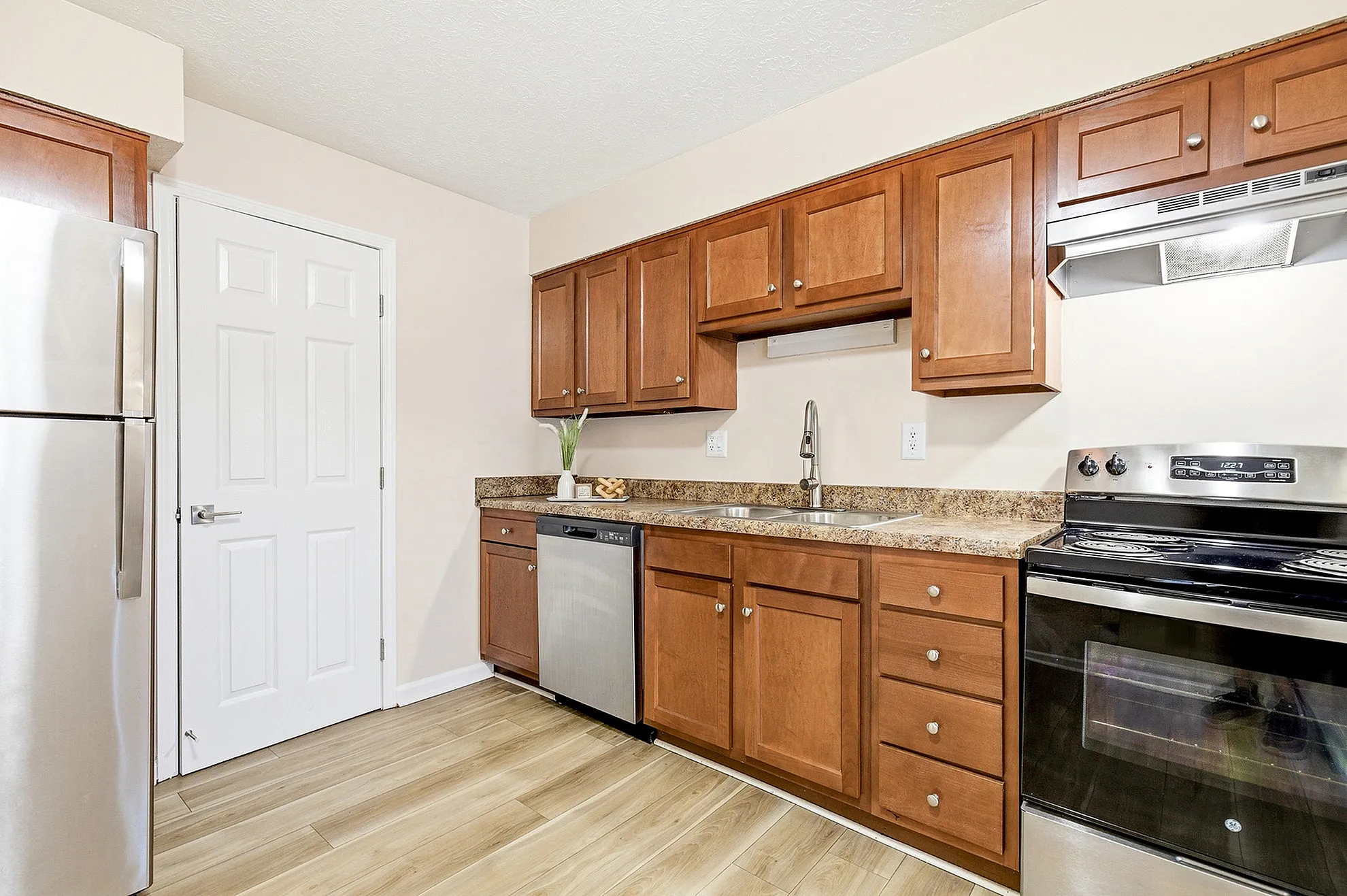 Modern kitchen with stainless steel appliances, elegant wooden cabinets, and a sleek countertop, creating a warm and inviting atmosphere.