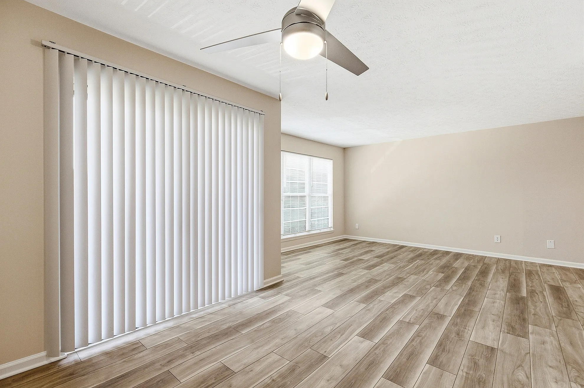 Bright and airy living space with elegant wood-style flooring and large windows in a modern apartment.