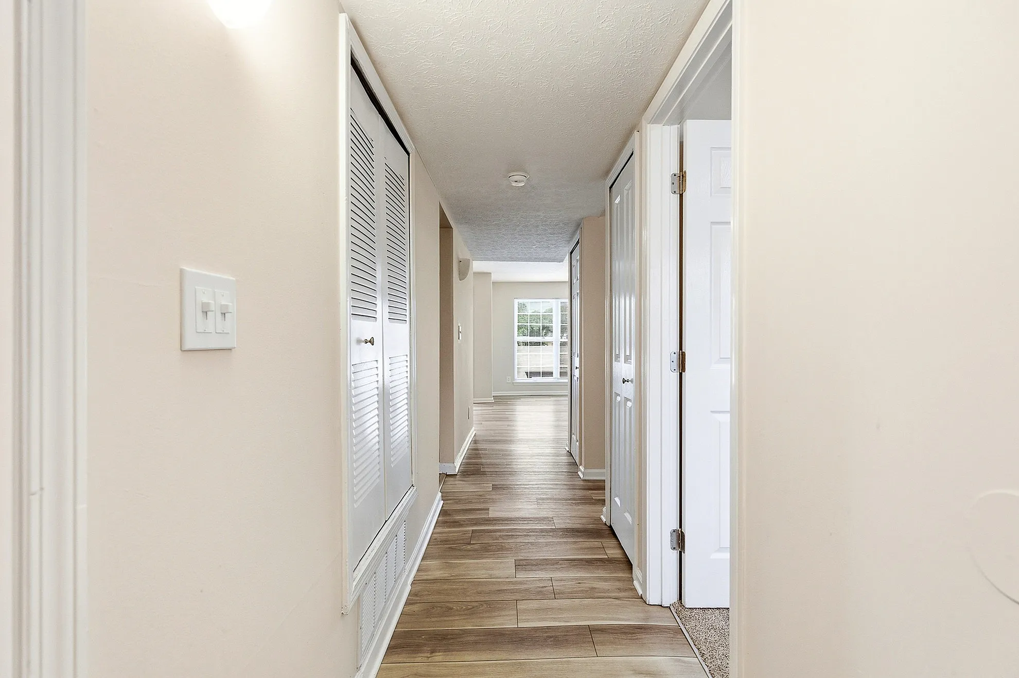 Bright hallway with elegant wood flooring and white doors leading to inviting living space.