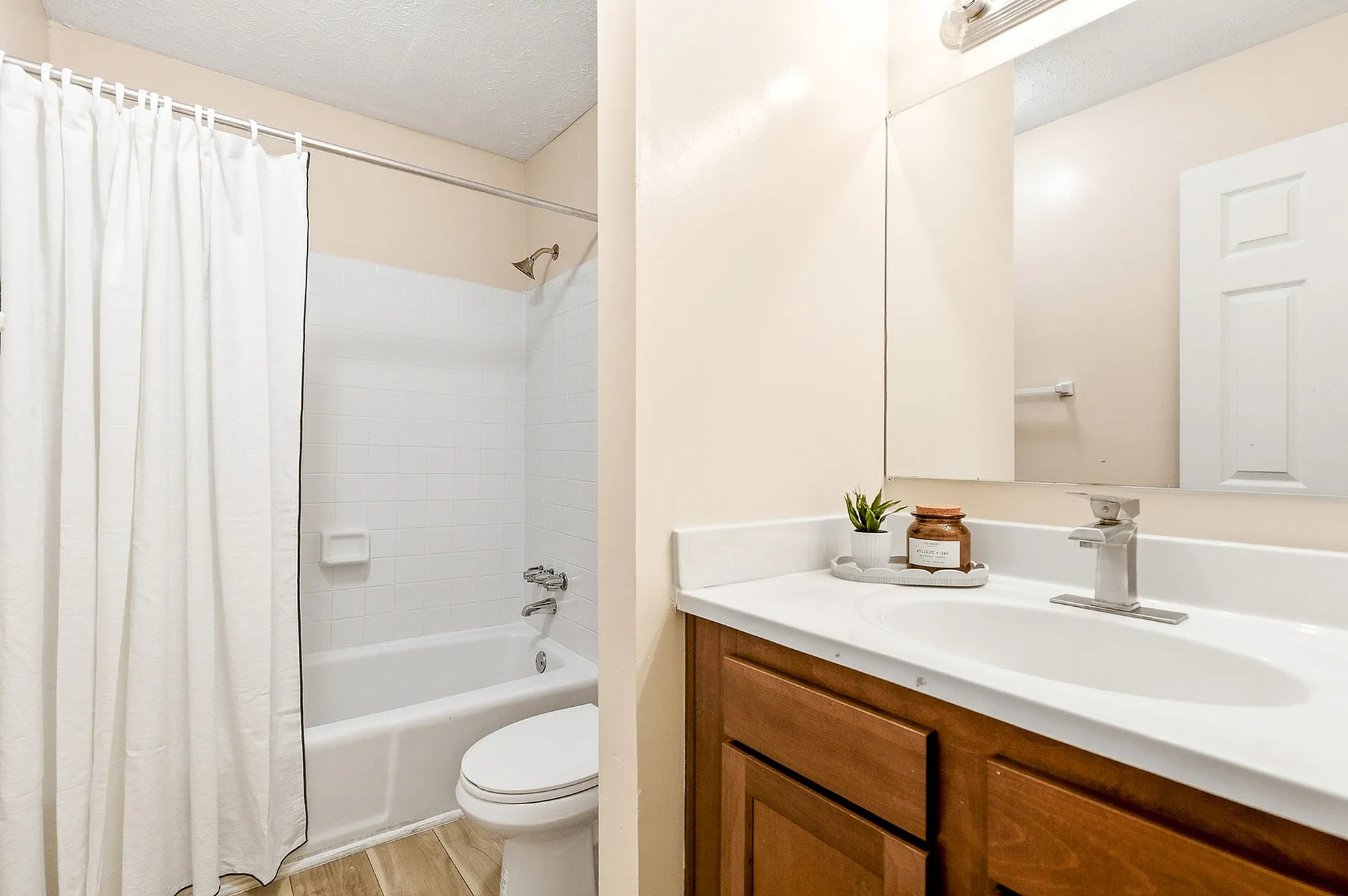 Bright and modern bathroom with elegant fixtures, featuring a cozy bathtub, stylish vanity, and charming decor accents.